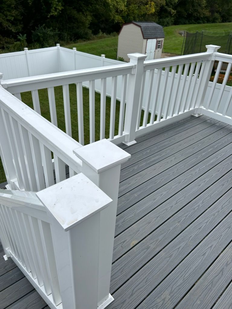 A deck with a white railing and a shed in the background.