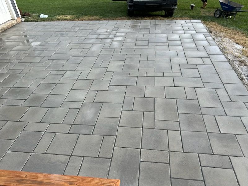 A patio with a wheelbarrow and a truck parked in the background