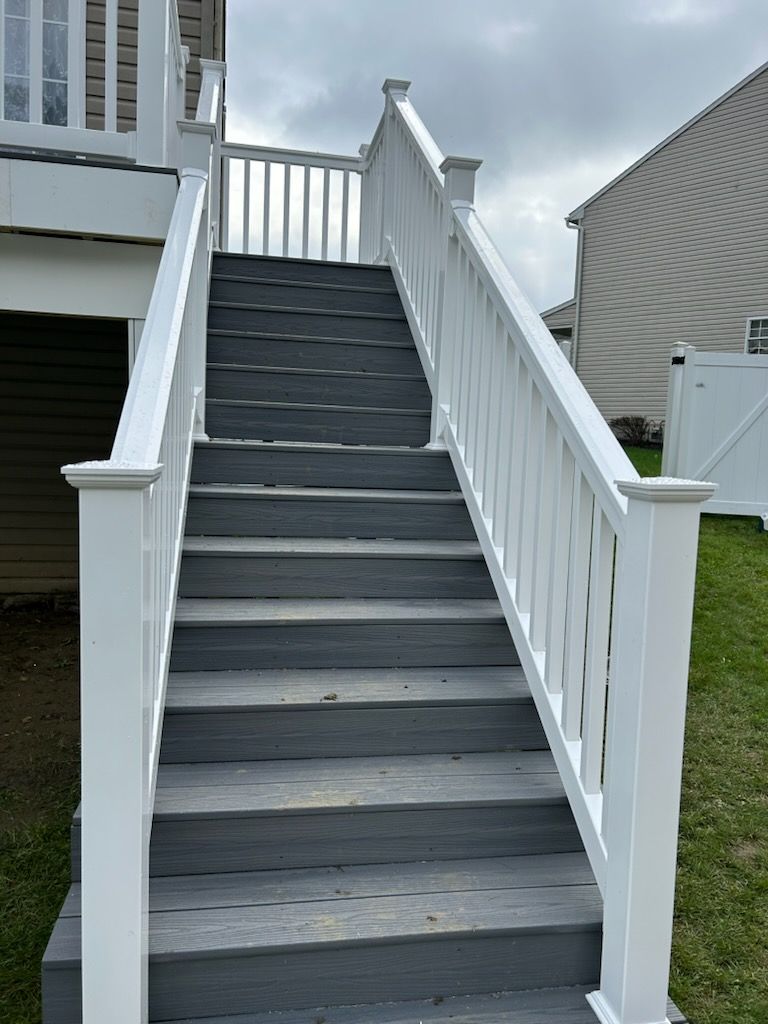 A set of stairs leading up to a deck with a white railing.