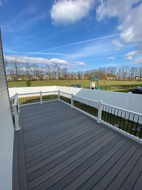A gray deck with a white railing and a white fence