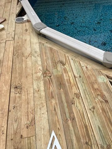 A wooden deck next to a swimming pool.