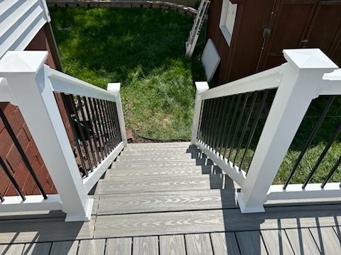 A wooden deck with stairs leading up to it and a white railing.