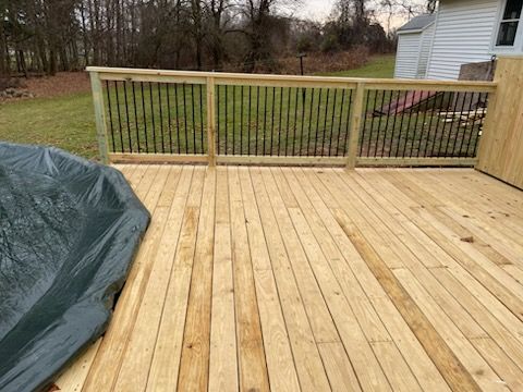 A wooden deck with a fence and a pool cover.