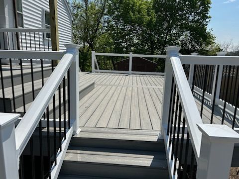 A deck with stairs leading up to it and a white railing.