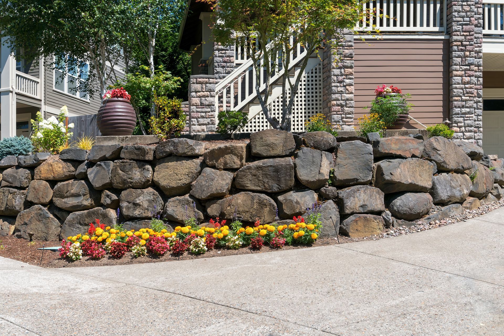 A Stone Wall With Flowers in Front of a House