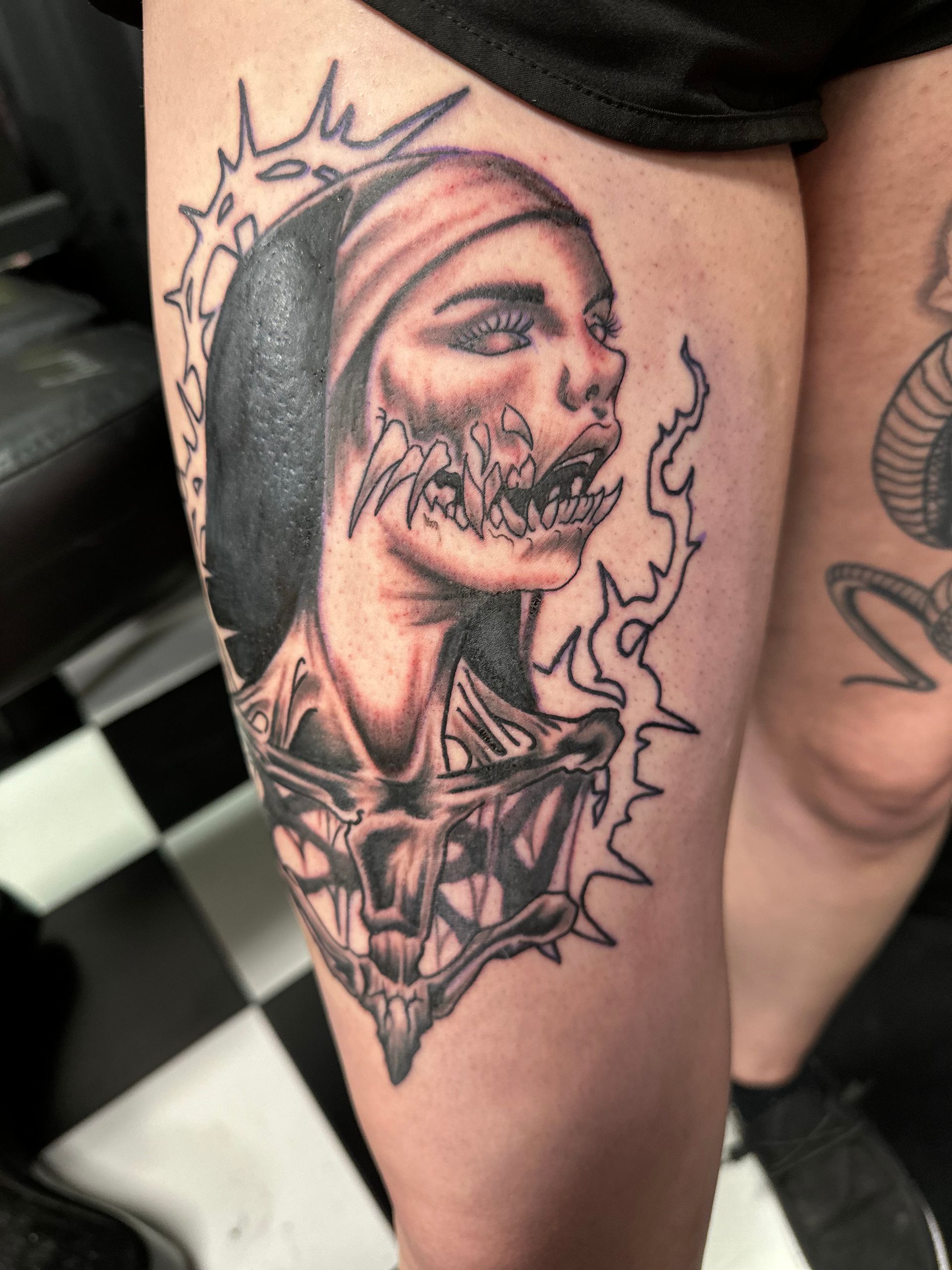 A woman has a tattoo of a nun on her leg
