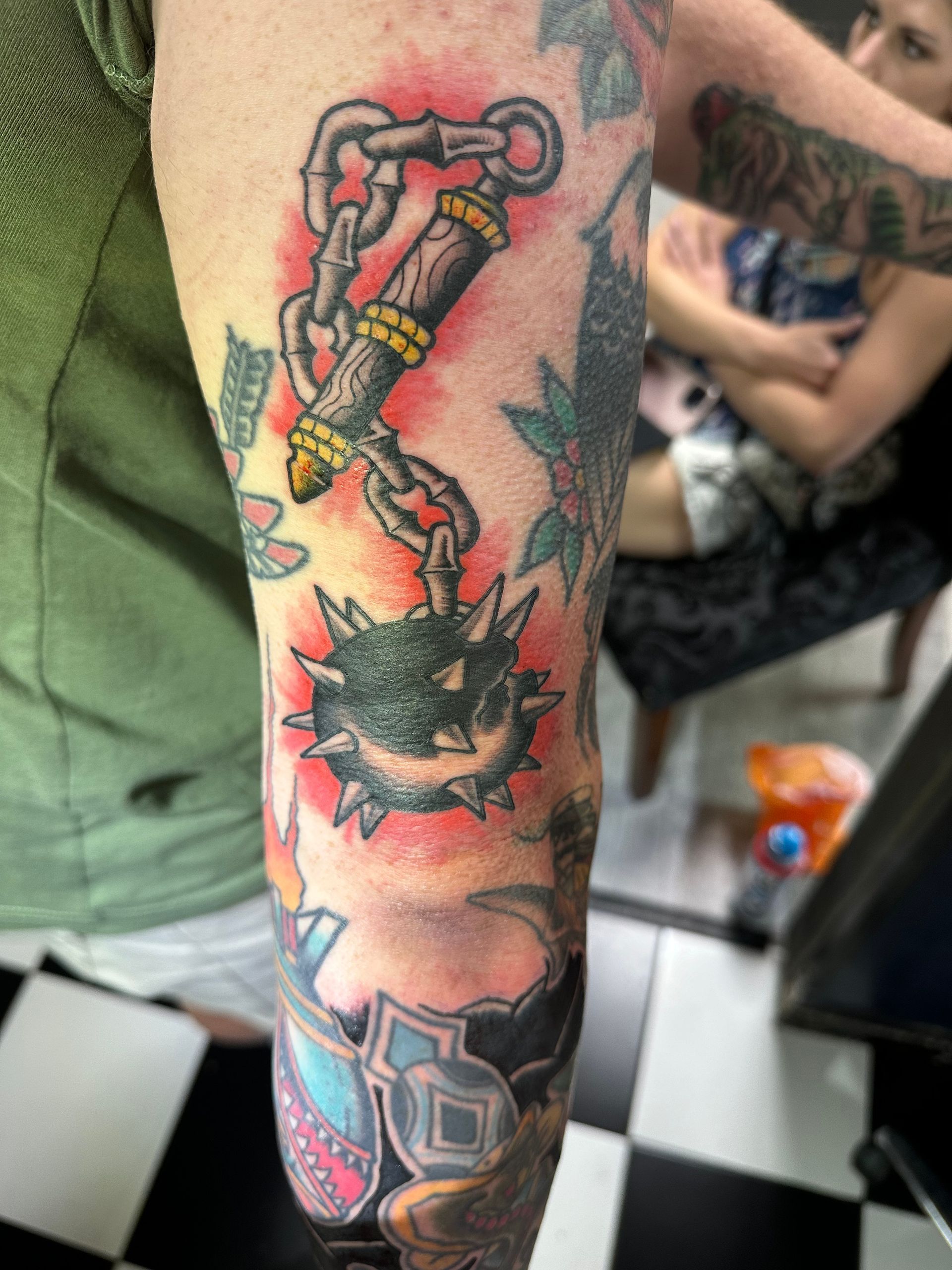 A person has a tattoo of a chained mace on their arm