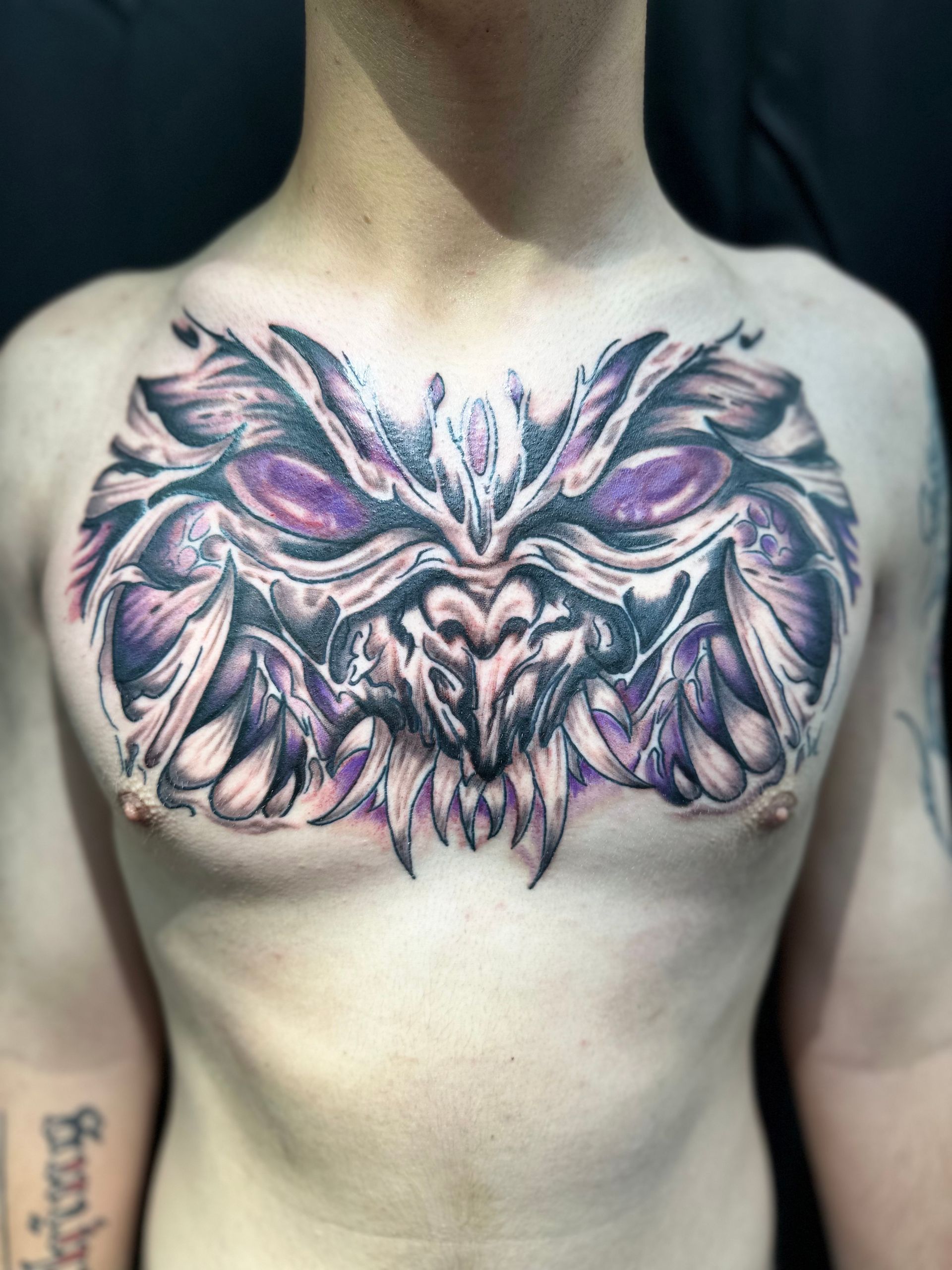 A man has a tattoo of a monster on his chest