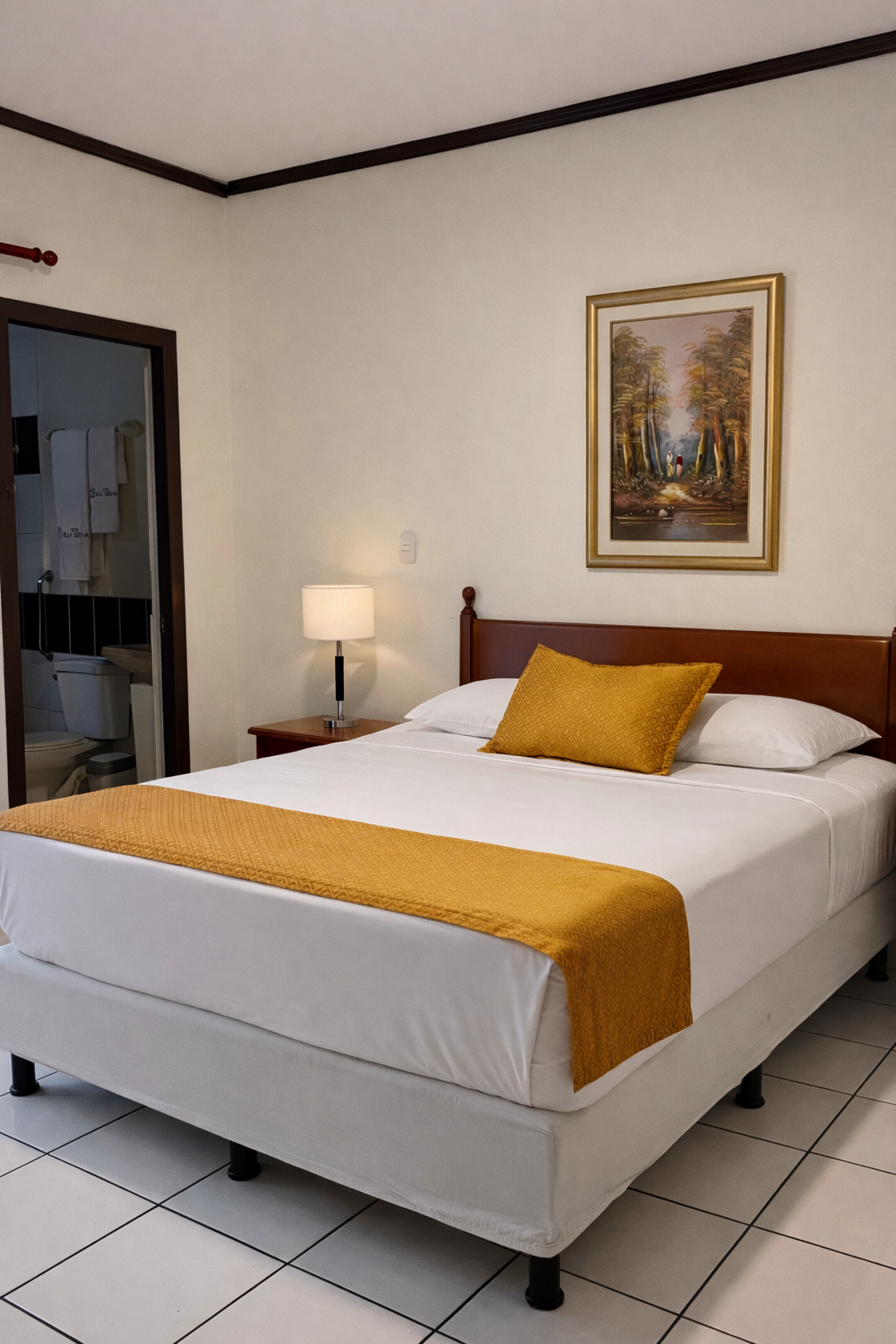 A bedroom with a queen-sized bed featuring white linens, a gold runner, and a gold pillow, beneath a landscape painting.