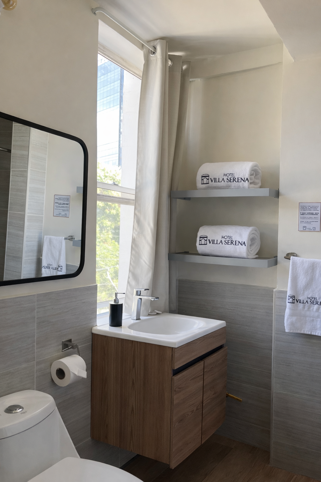 Modern bathroom with a wooden vanity, white sink, mirror, toilet, window with white curtains, and two shelves with towels.