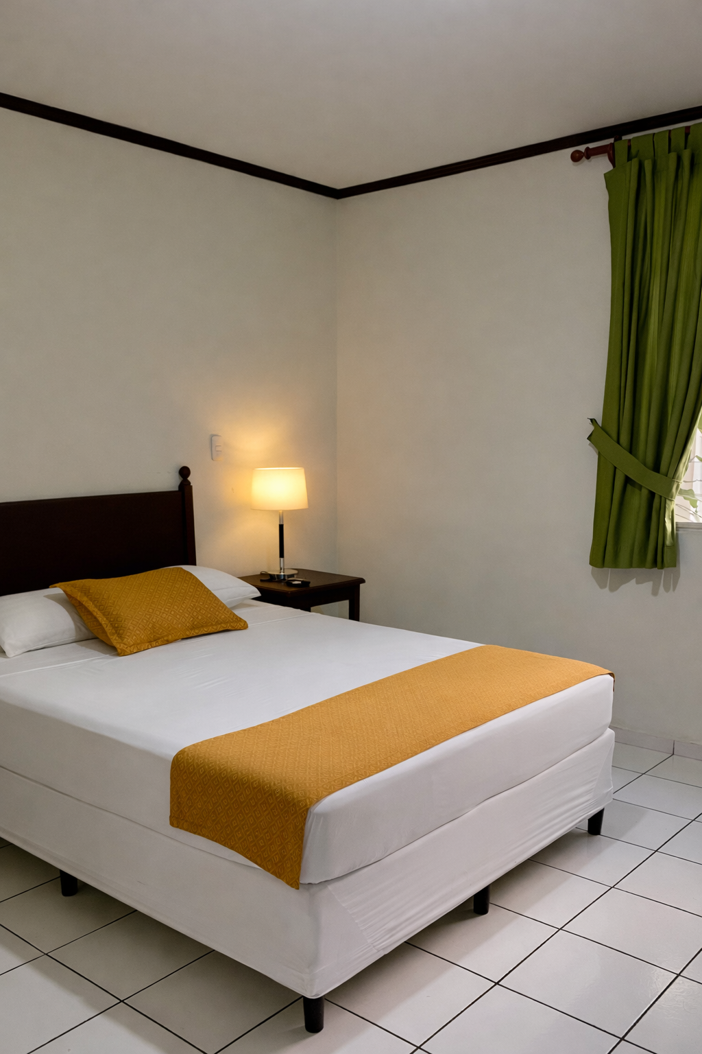 A bedroom with a bed featuring white linens, a yellow runner and pillow, a nightstand with a lamp, and green curtains.