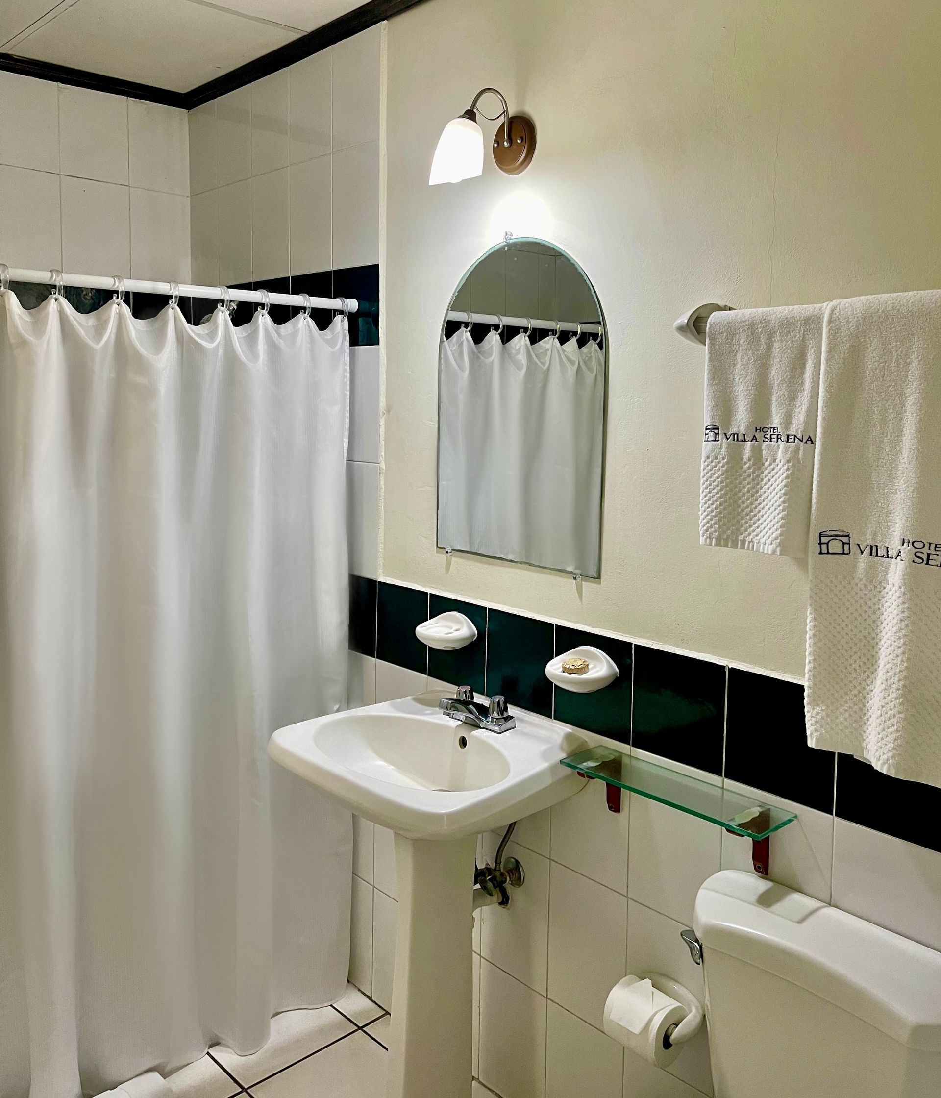 A bathroom with a sink , toilet , mirror and shower curtain.
