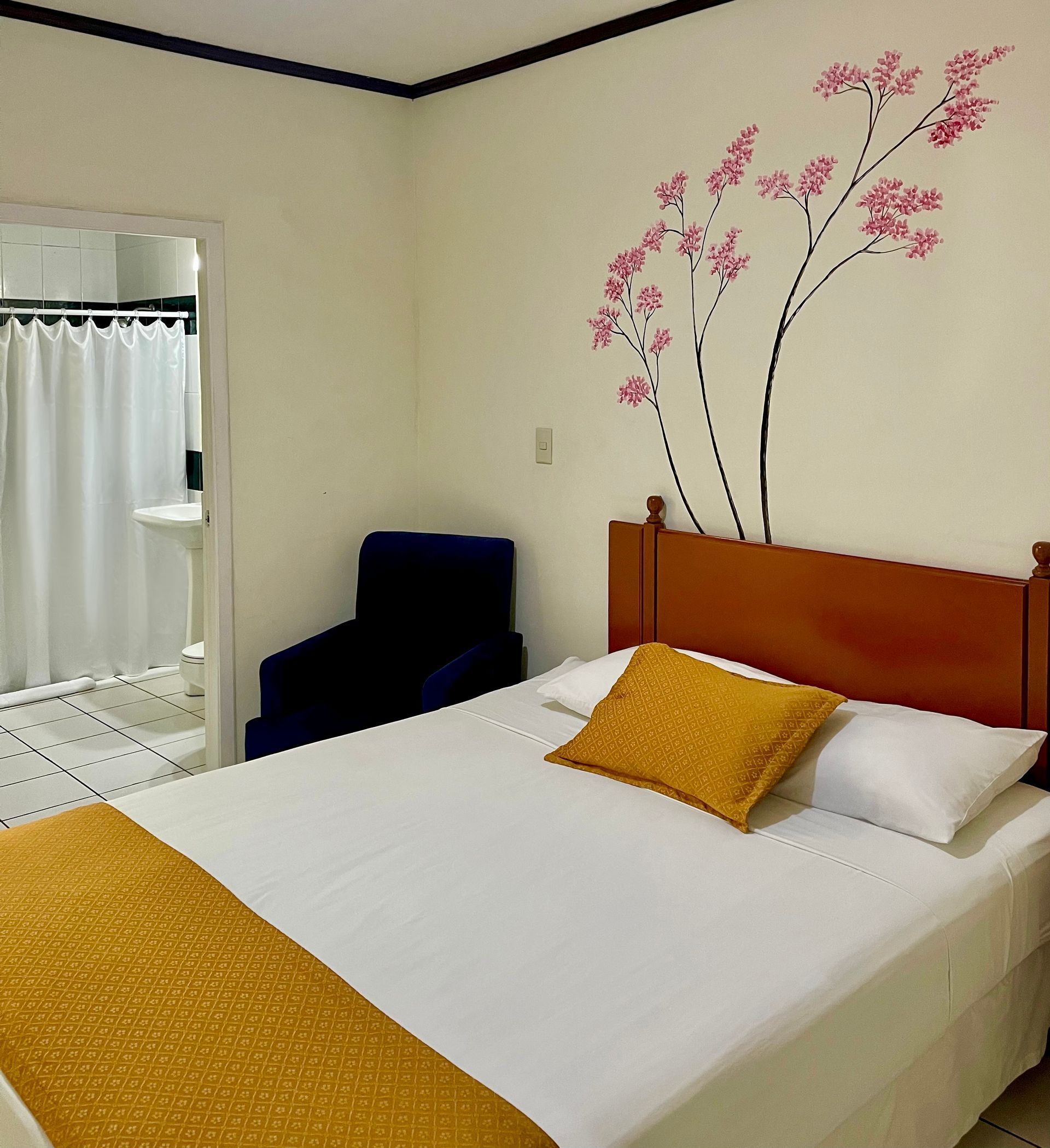 A bedroom with a bed and a chair with flowers on the wall