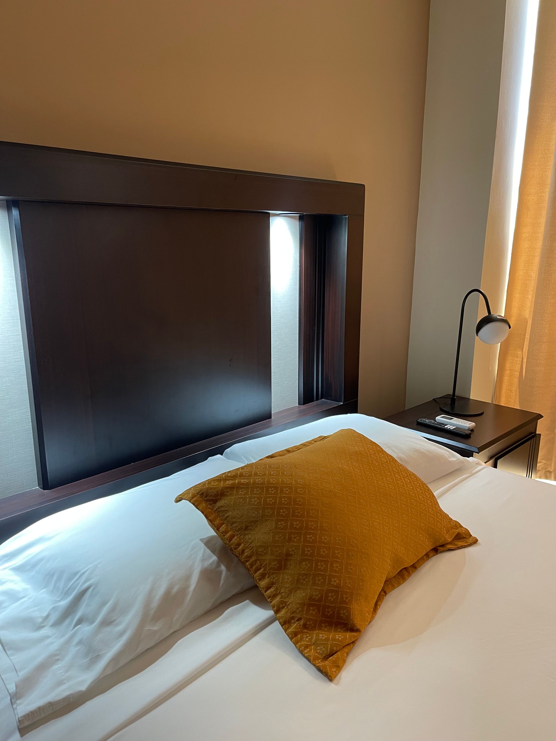 A bed with a yellow pillow on it in a hotel room