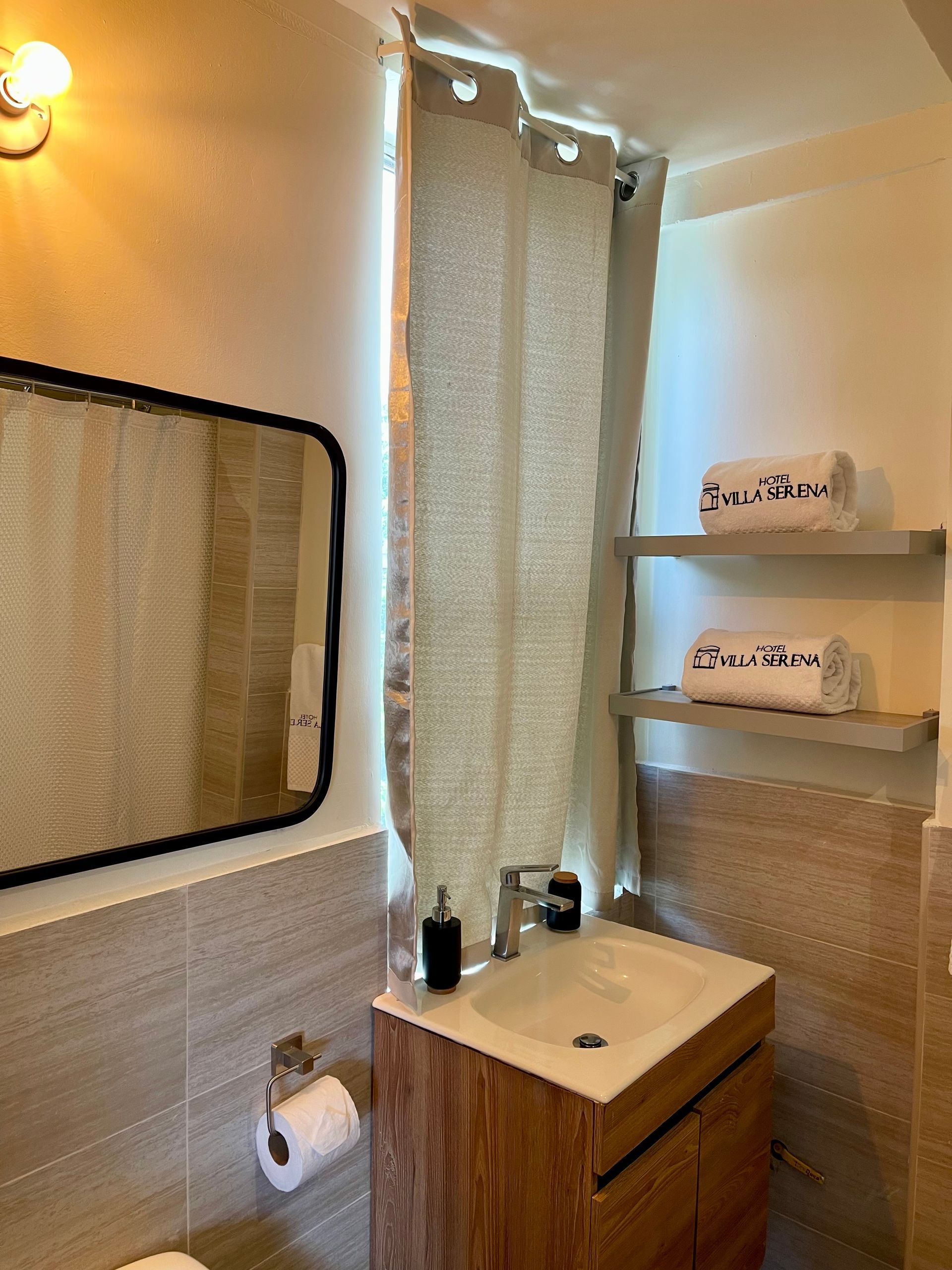A bathroom with a sink , mirror and towels on shelves.