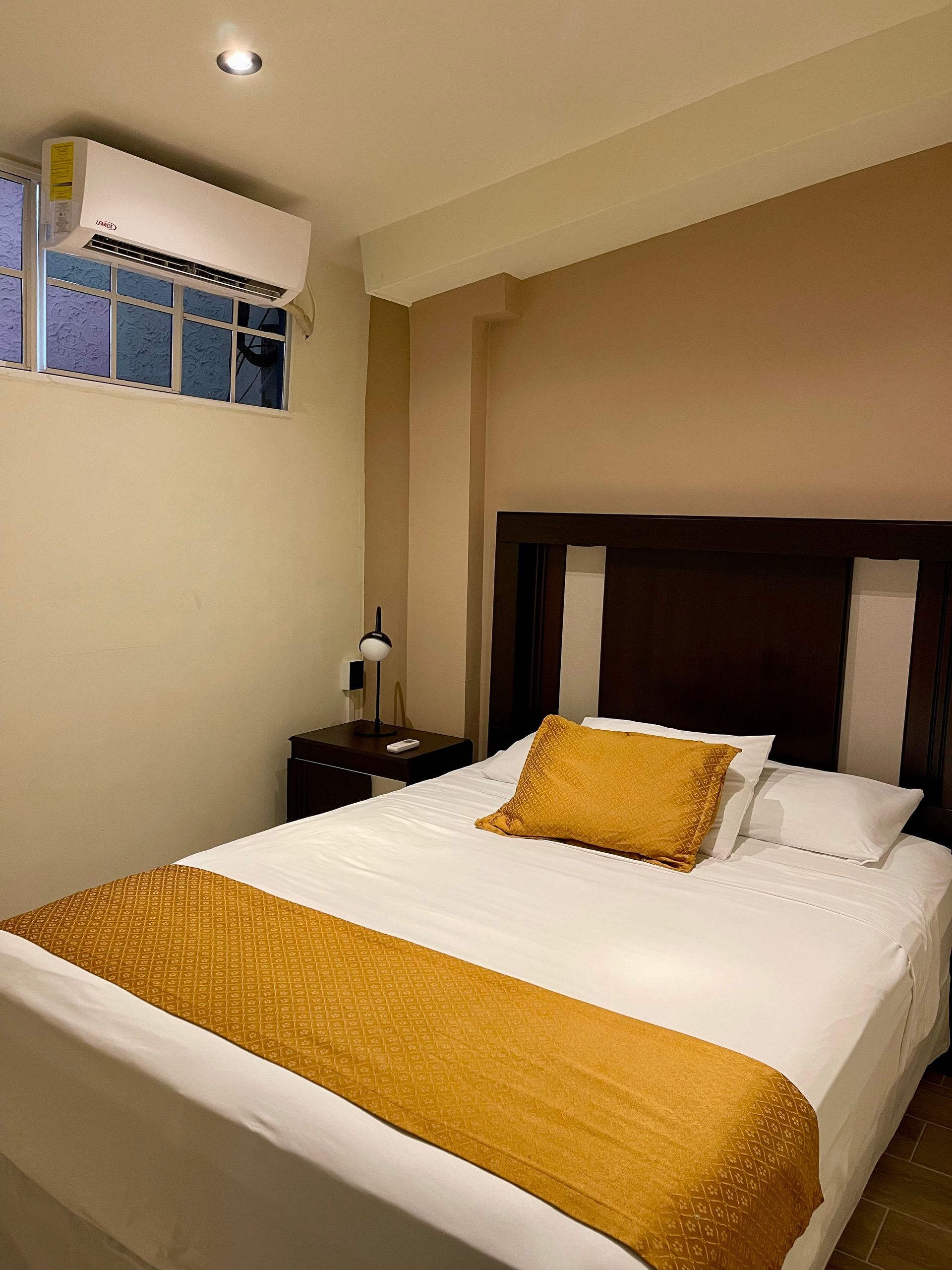 A bedroom with a bed , nightstand and air conditioner