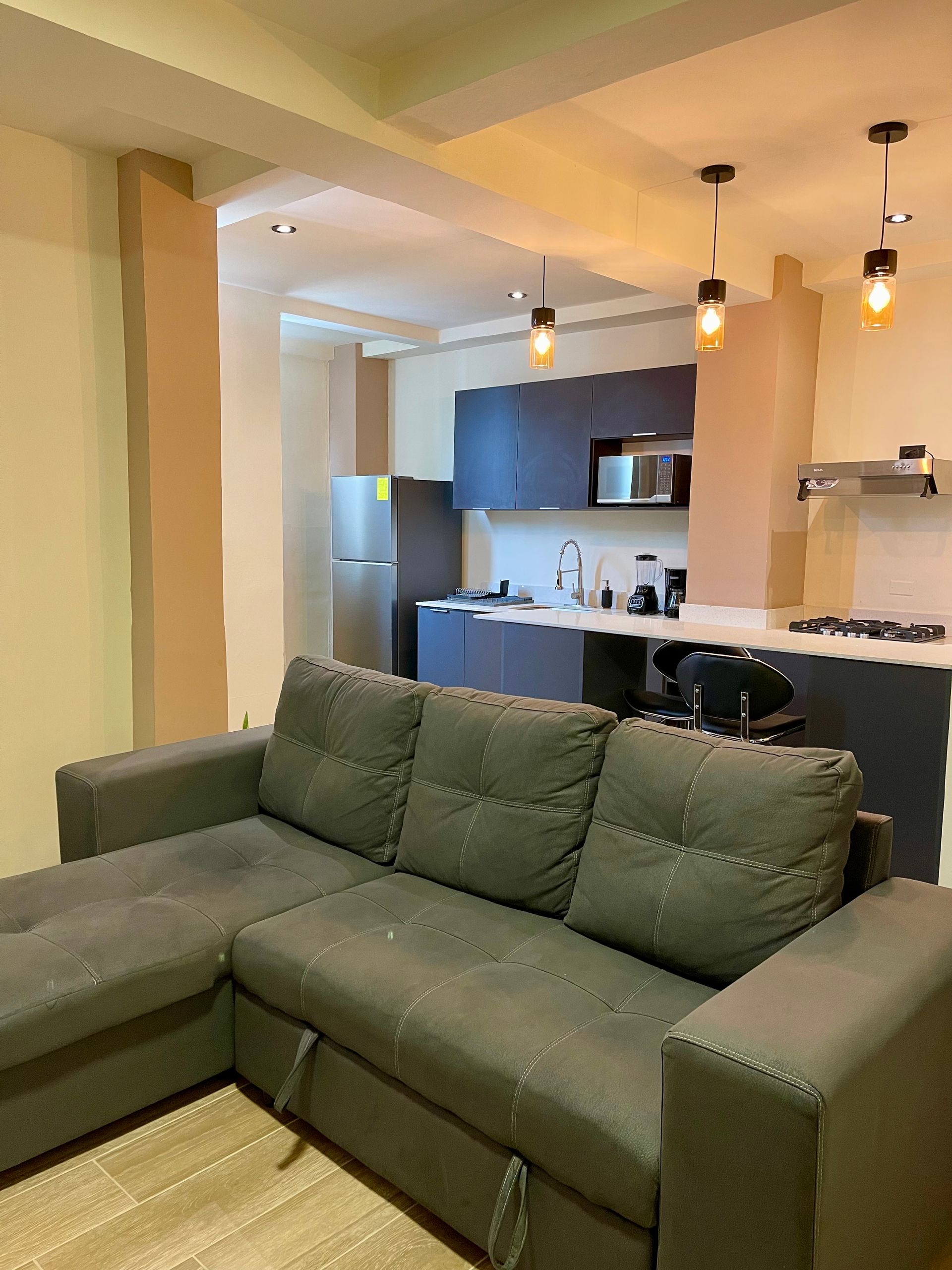 A living room with a couch and a kitchen in the background