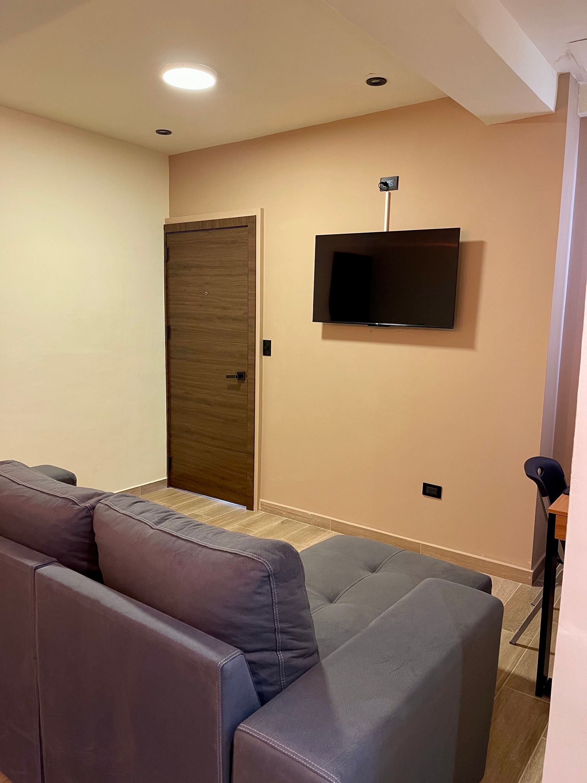 A living room with a couch and a flat screen tv on the wall.