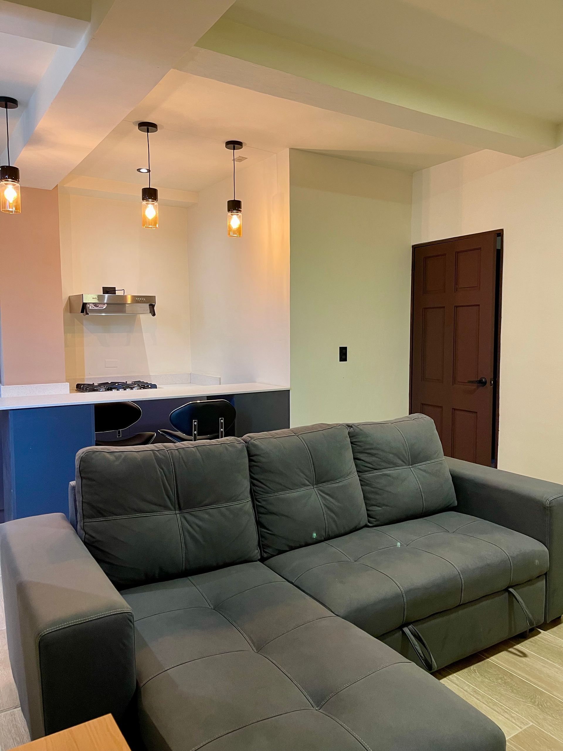 A living room with a couch and a kitchen in the background