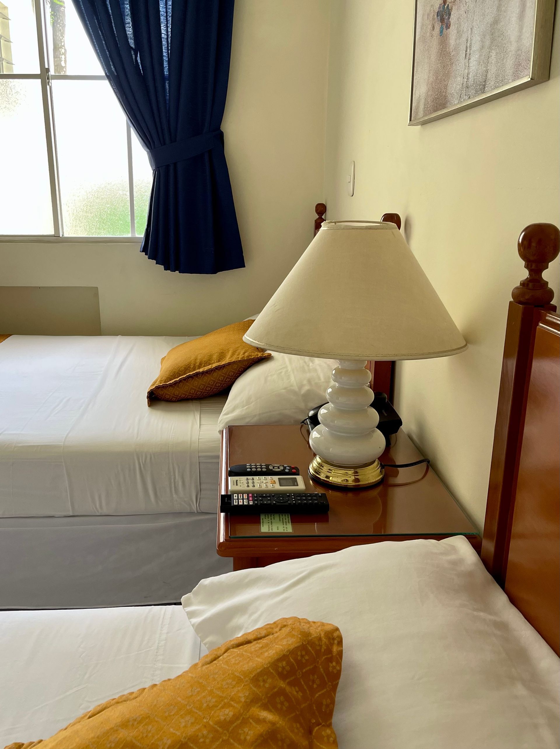 A bedroom with two beds and a lamp on a nightstand