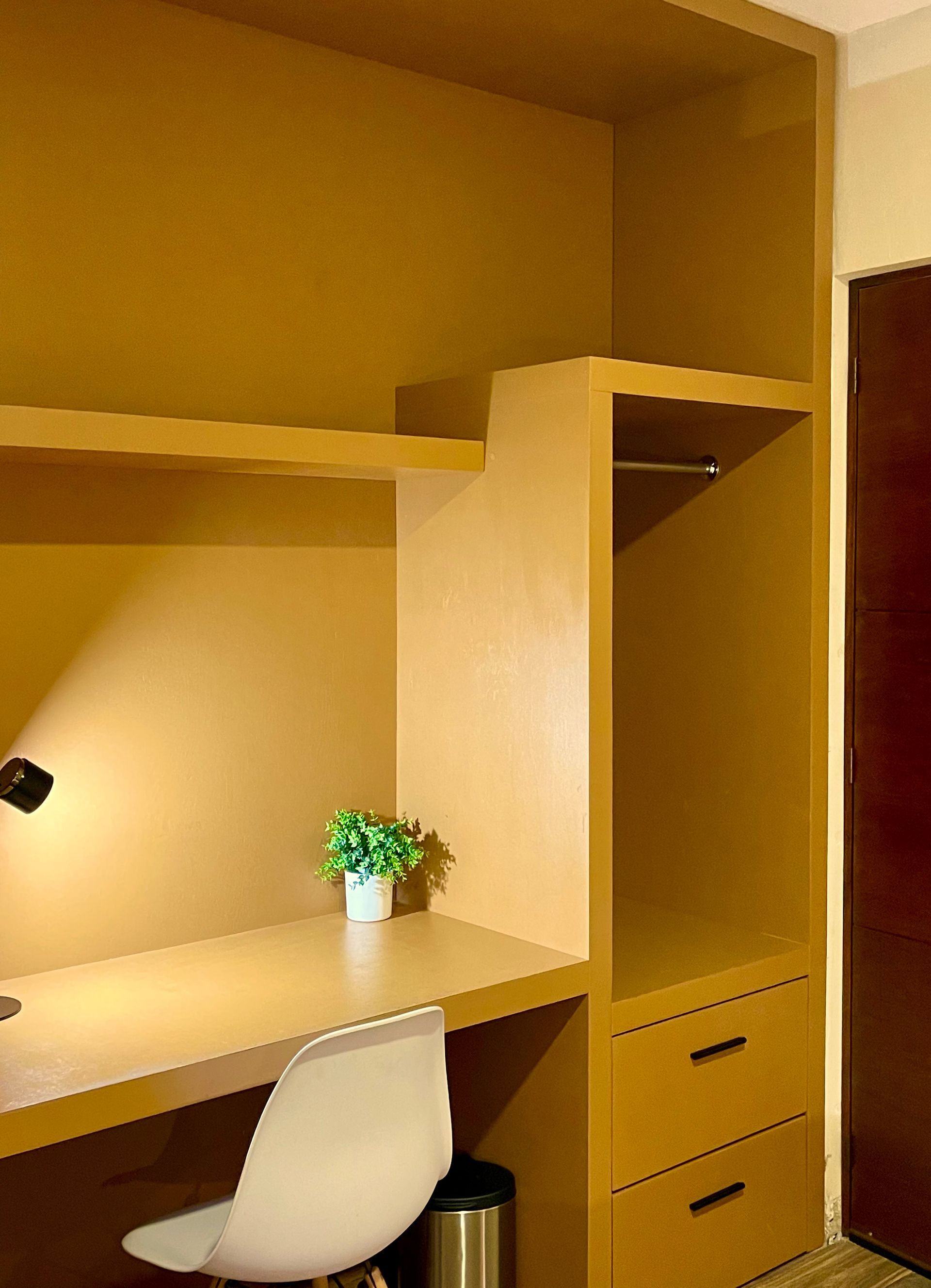 A desk with a lamp and a potted plant on it in a room.