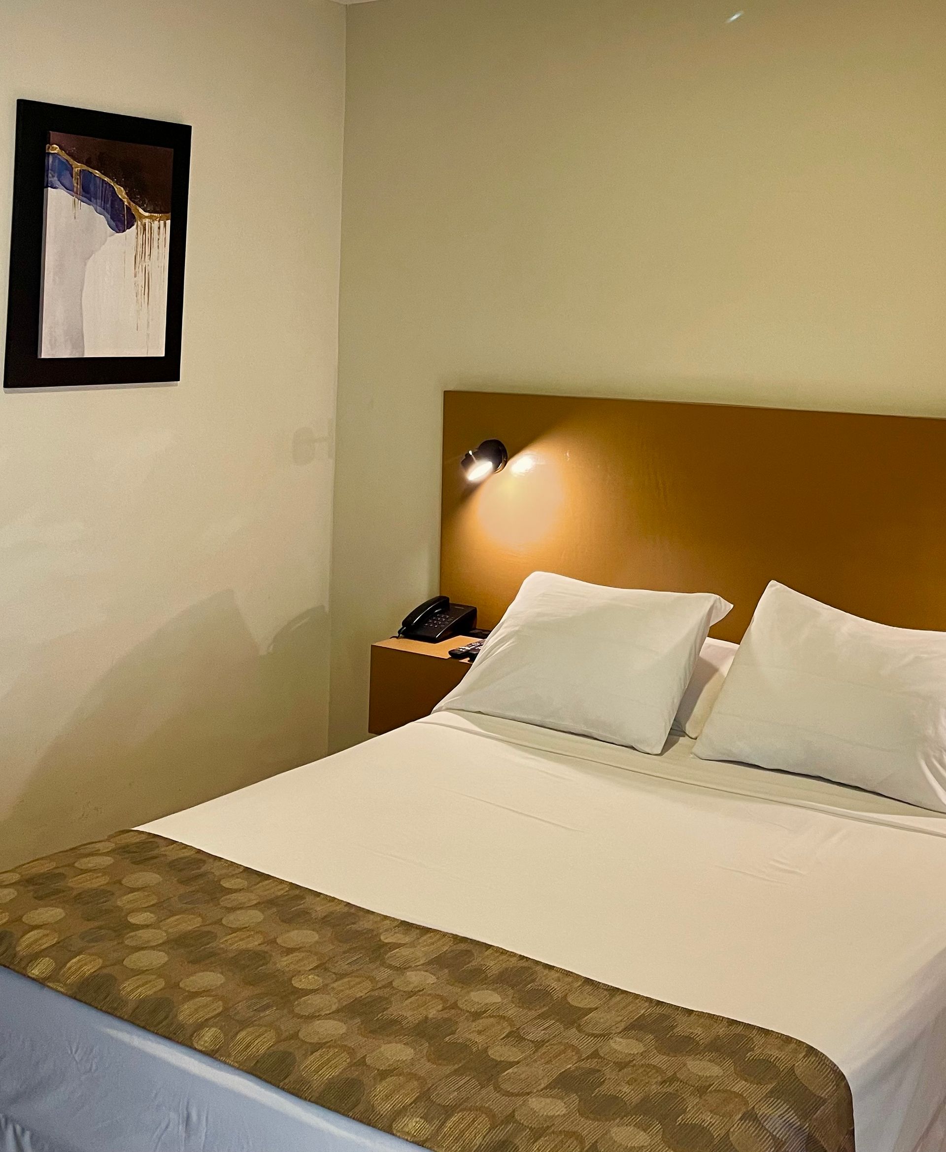 A hotel room with a bed and a picture on the wall