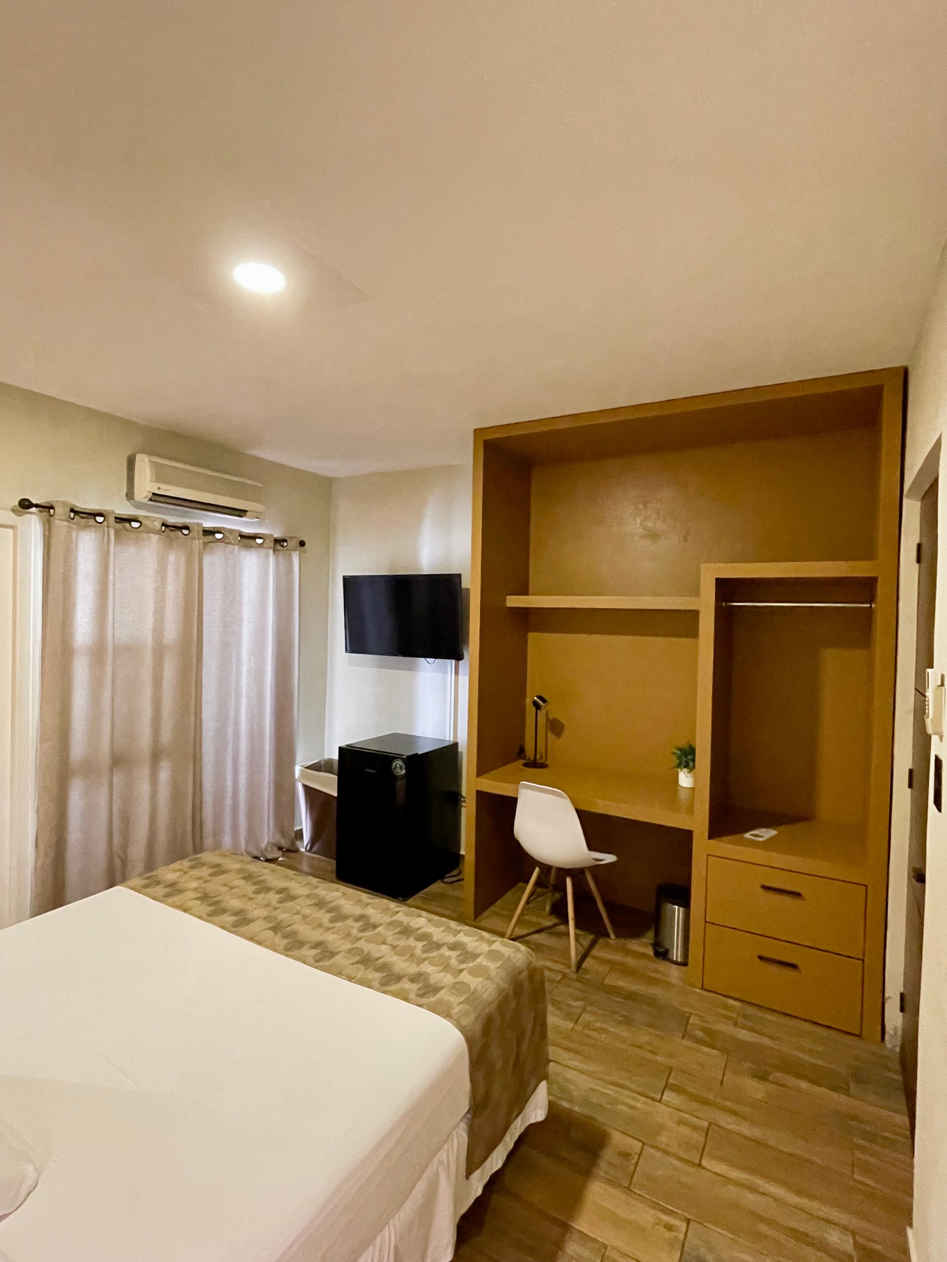 A hotel room with a bed , desk and television.