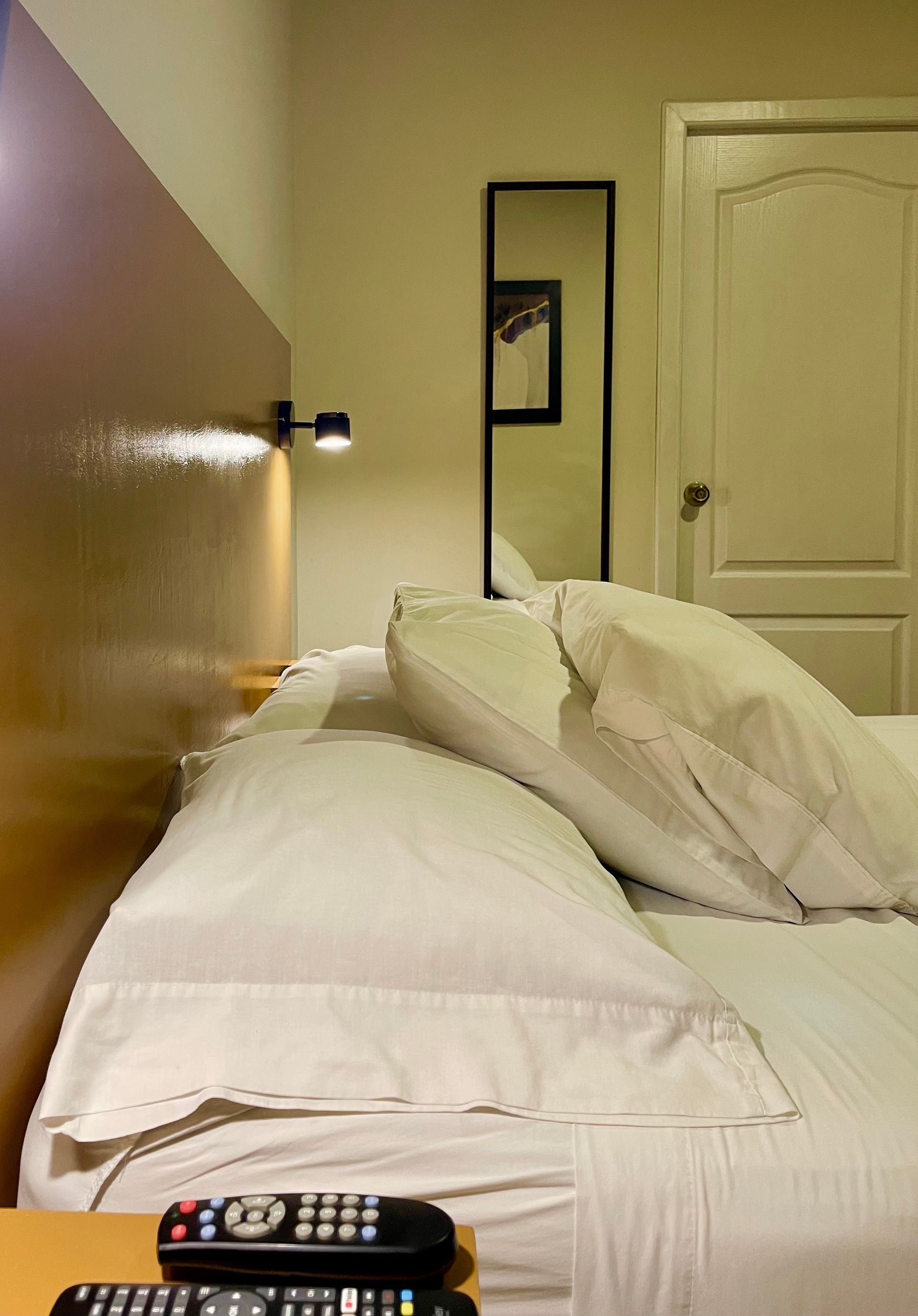 A bed with white sheets and pillows in a hotel room