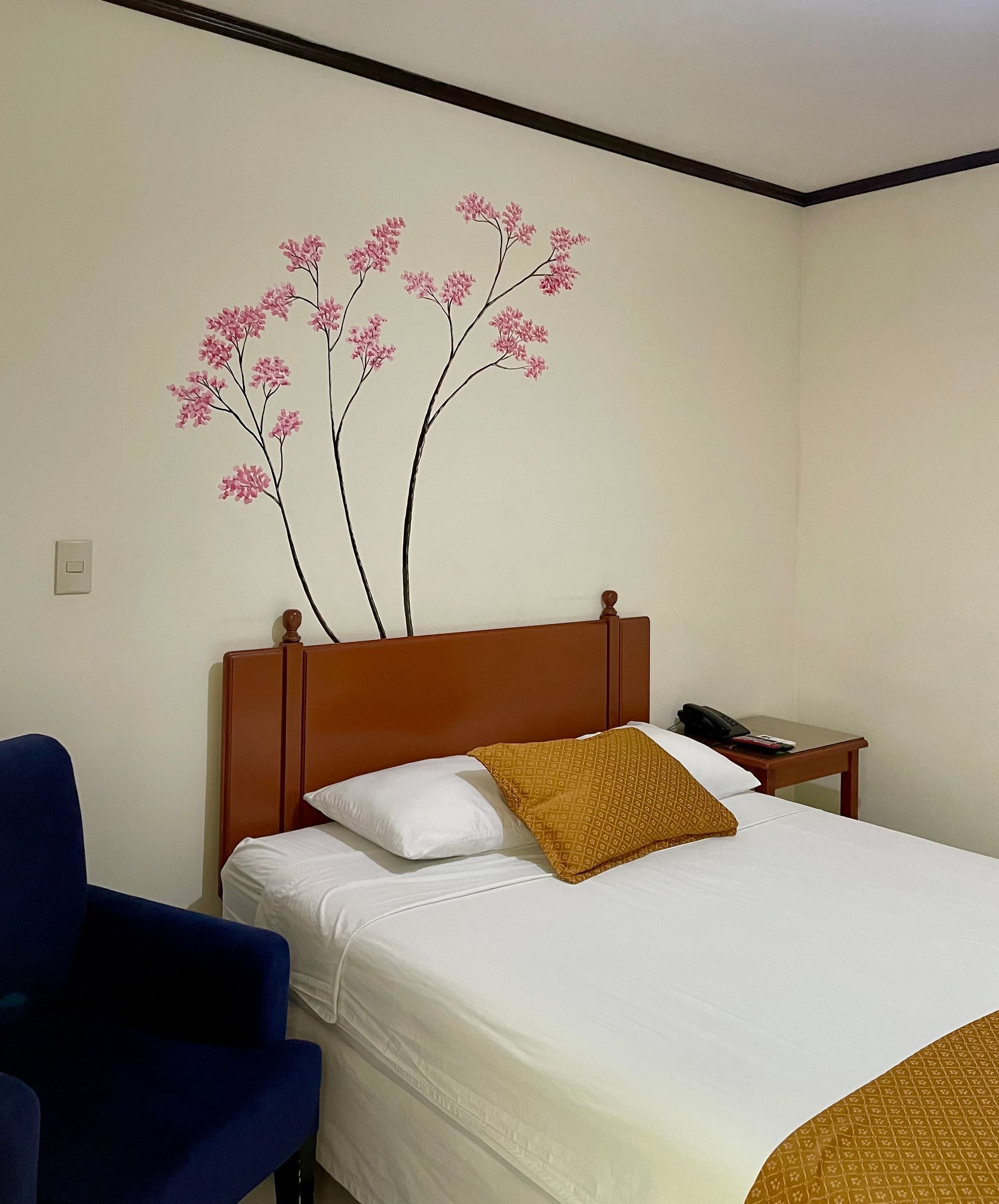 A bedroom with a bed and a chair with flowers on the wall