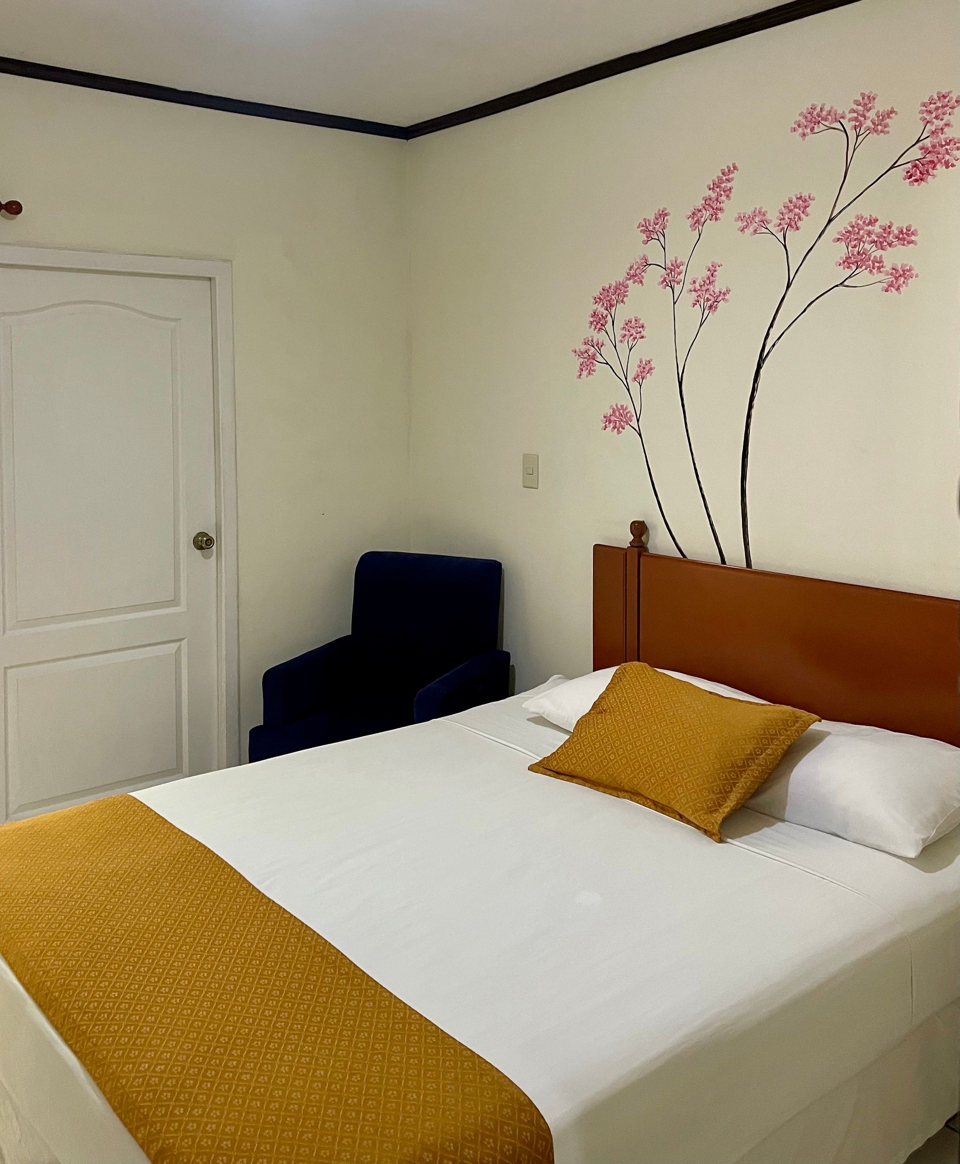 A bedroom with a bed and a chair with flowers on the wall