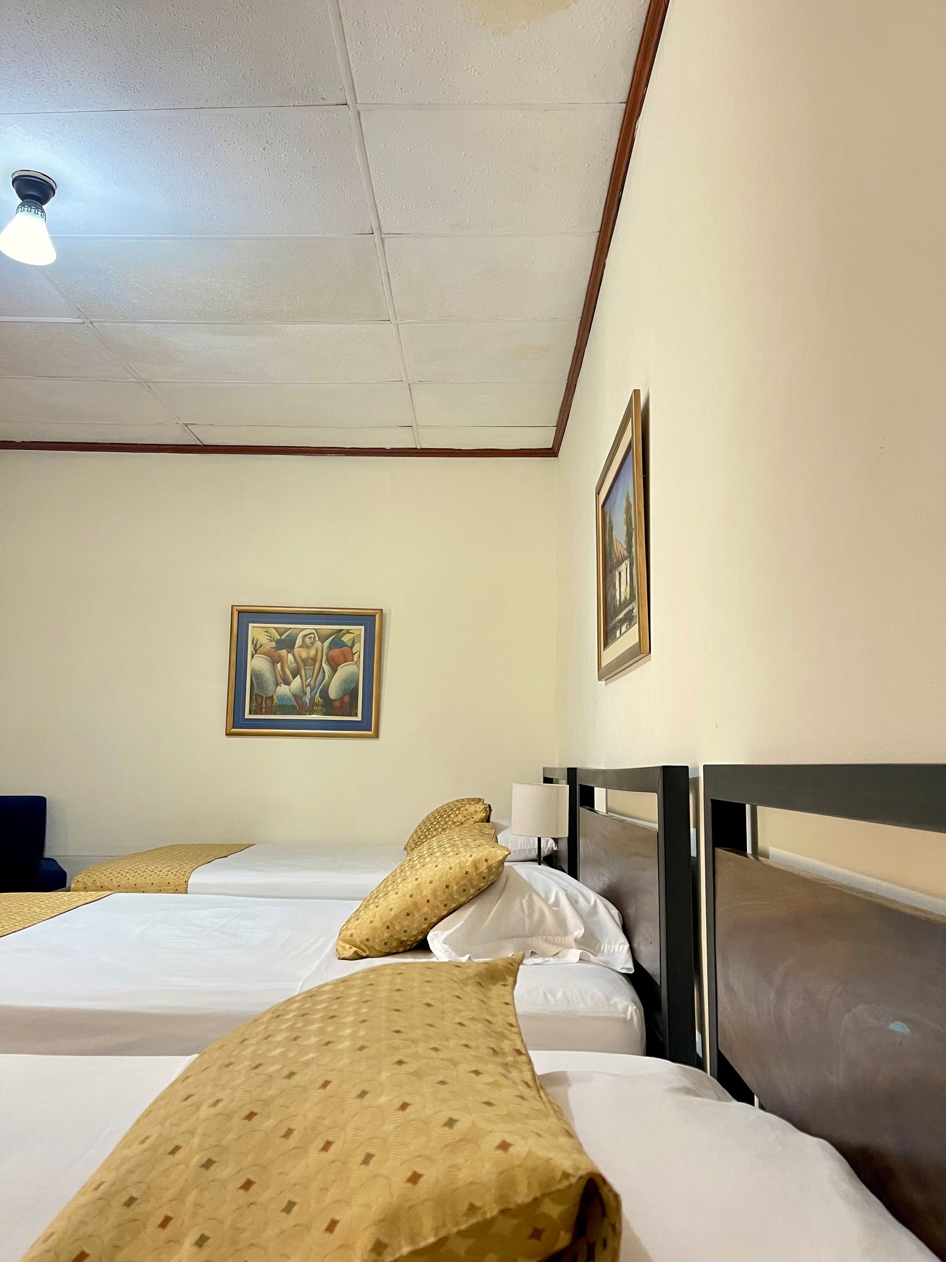 A hotel room with three beds and a painting on the wall