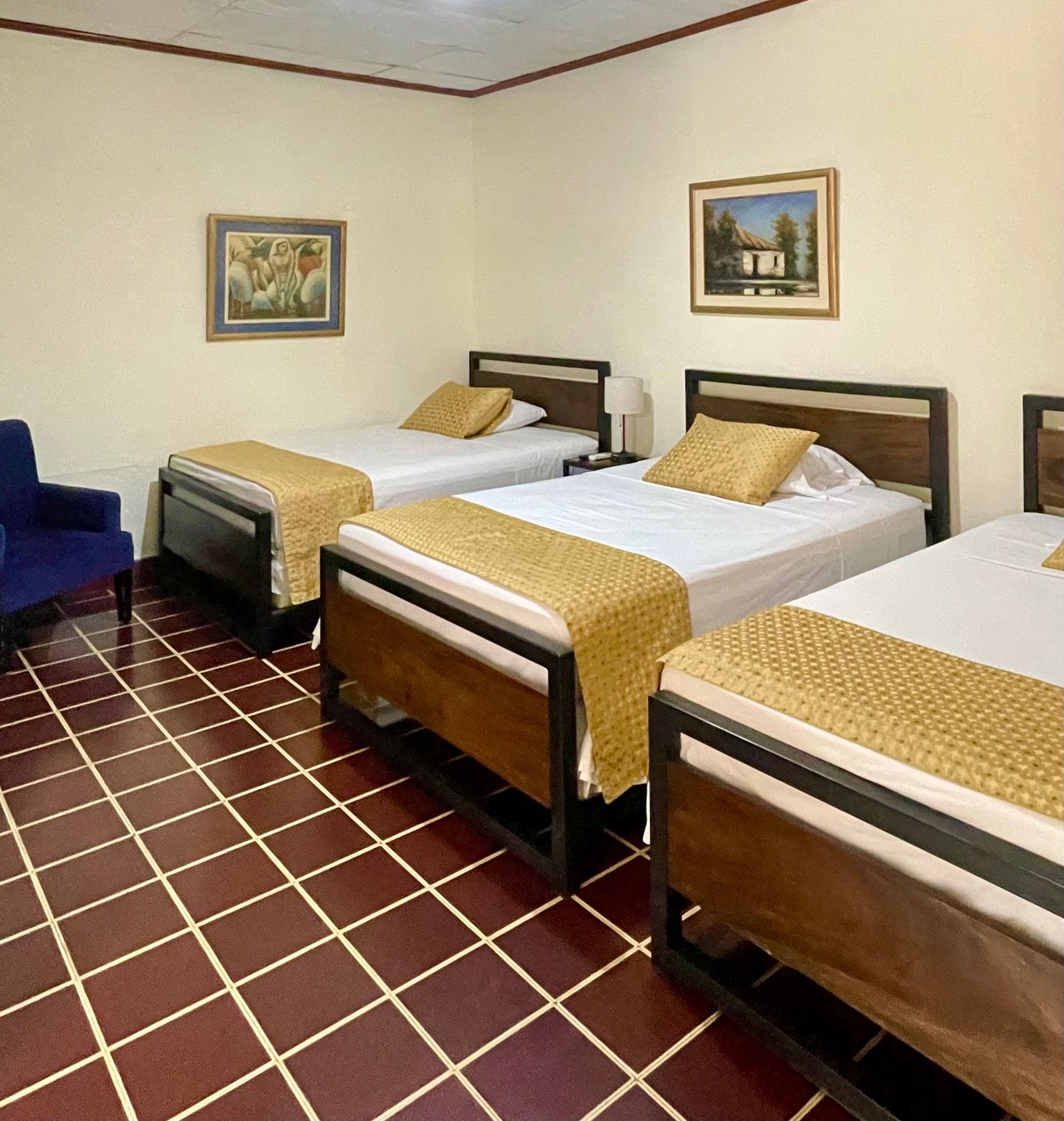 A hotel room with three beds and a chair