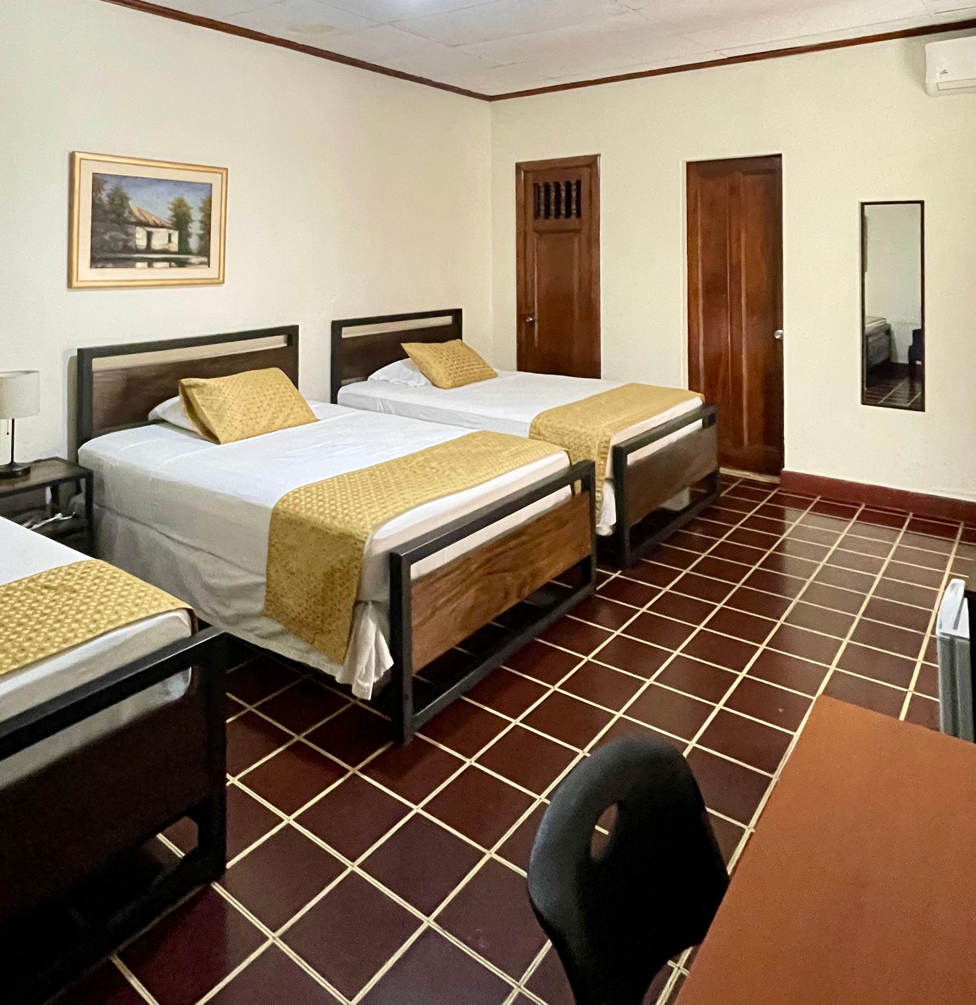 A hotel room with three beds and a desk