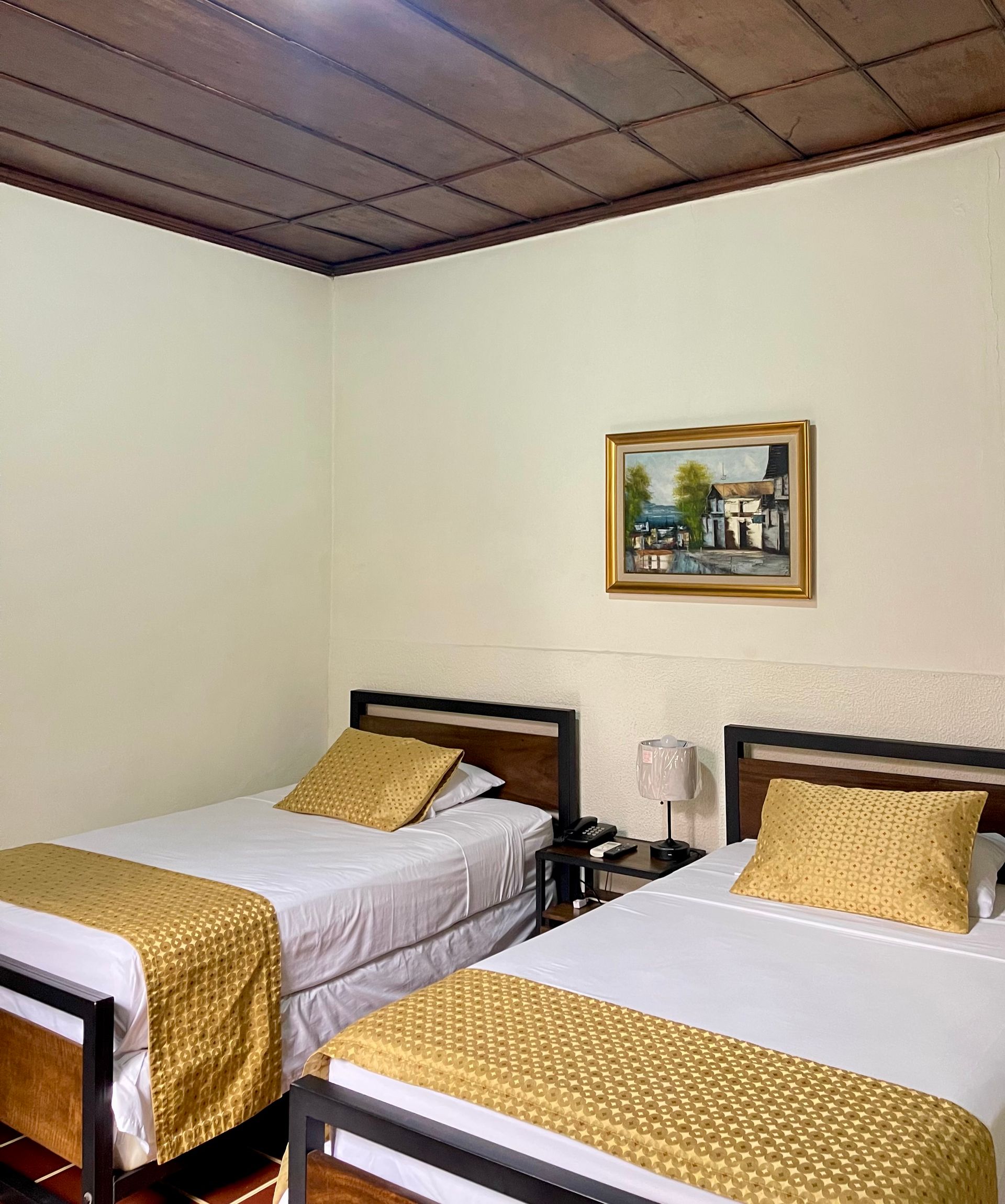 A bedroom with two beds and a painting on the wall.