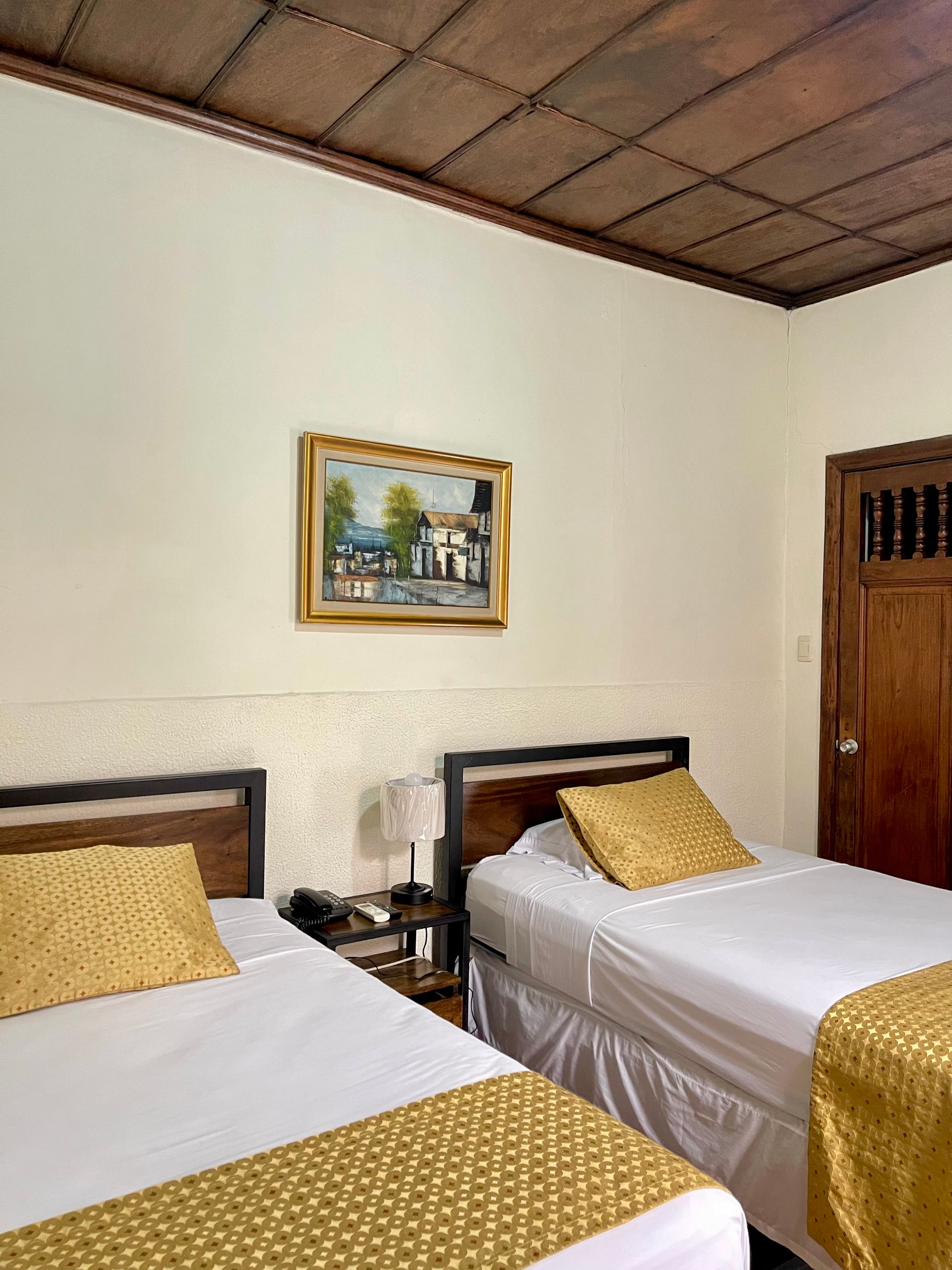 A hotel room with two beds and a painting on the wall