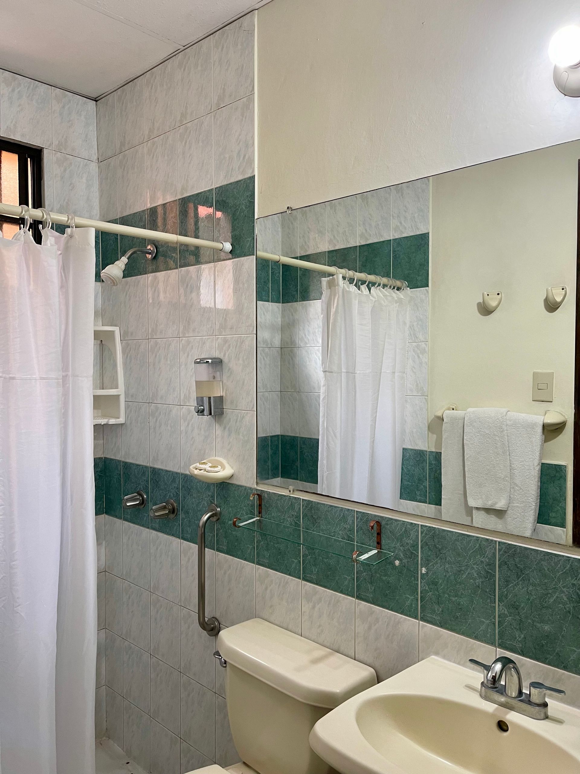 A bathroom with a toilet , sink and mirror