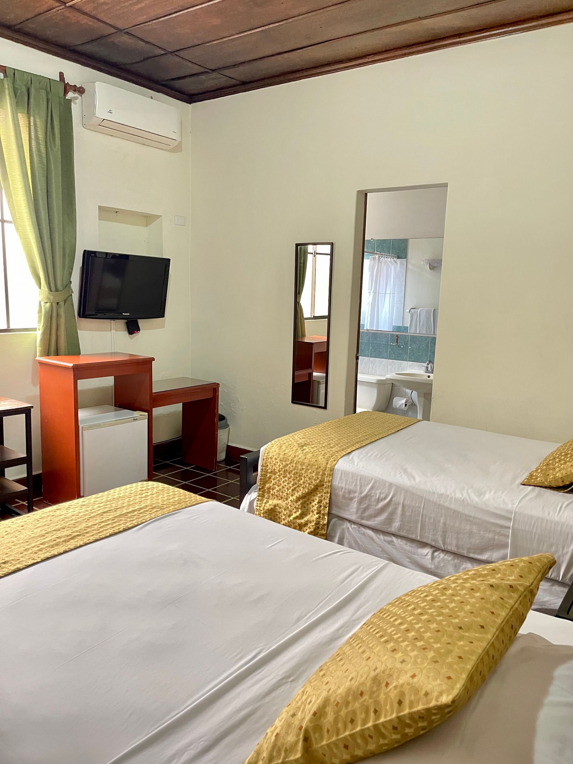 A hotel room with two beds , a desk , a television and a mirror.