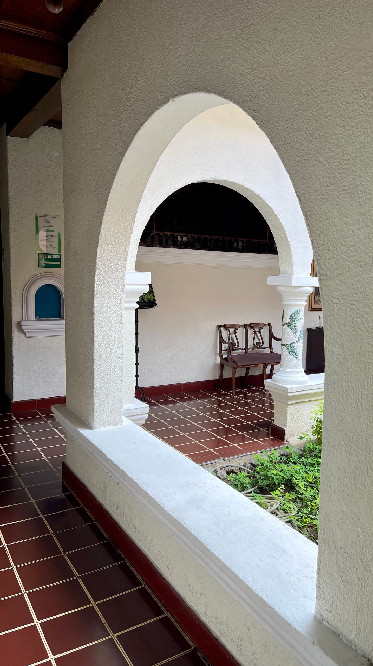 A hallway with a white archway and a bench