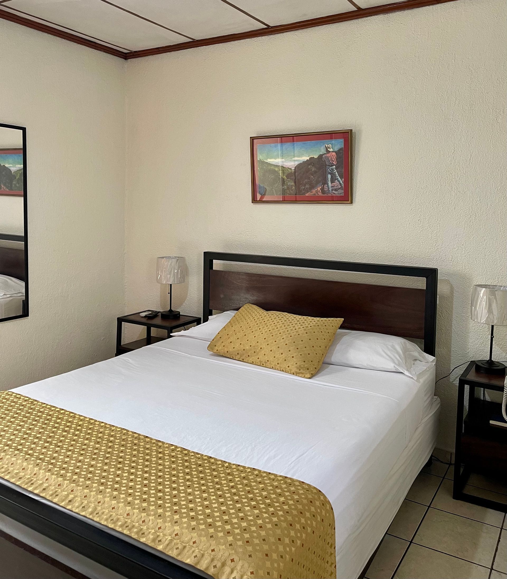 A bedroom with a bed and a mirror on the wall