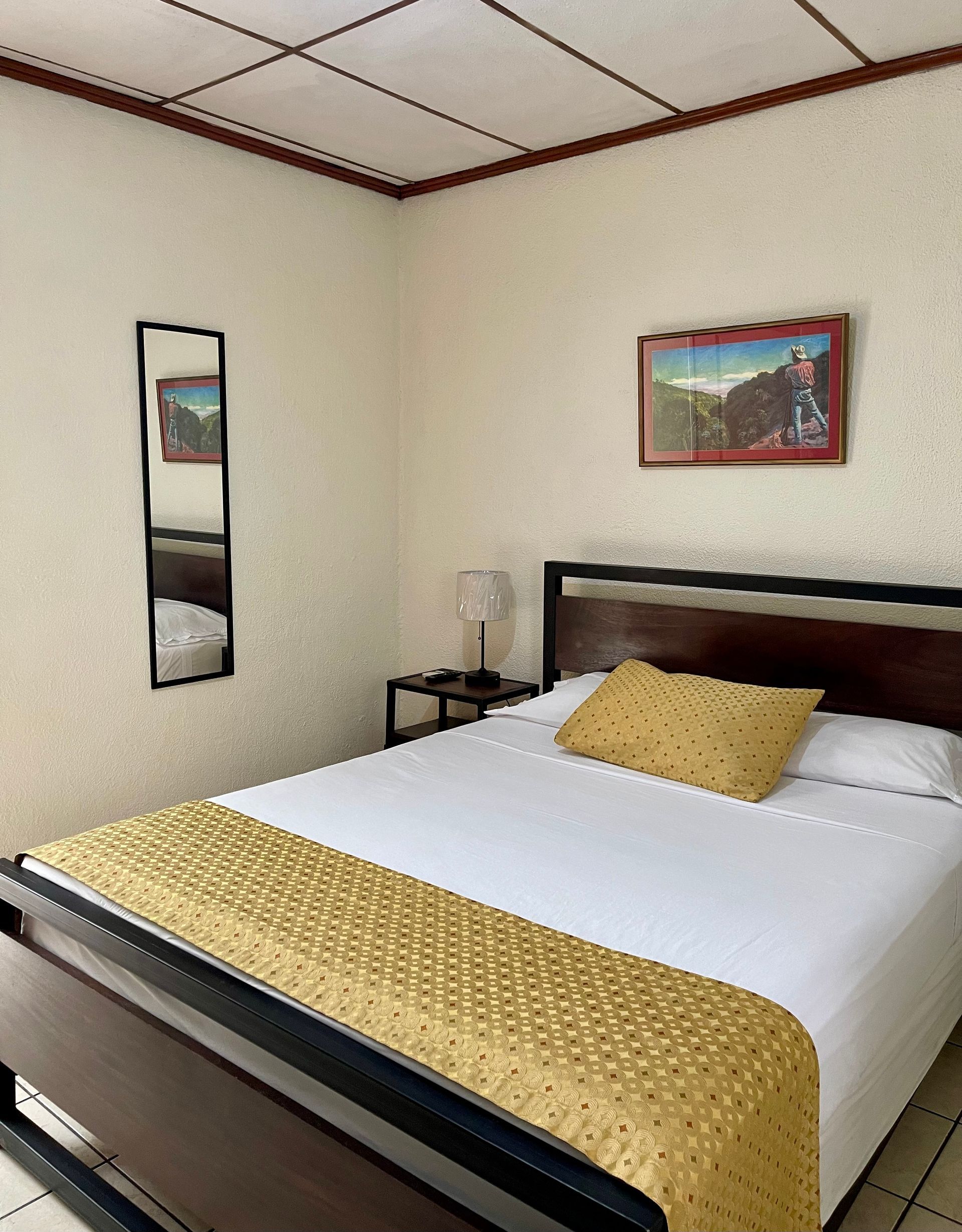 A hotel room with a bed and a mirror on the wall