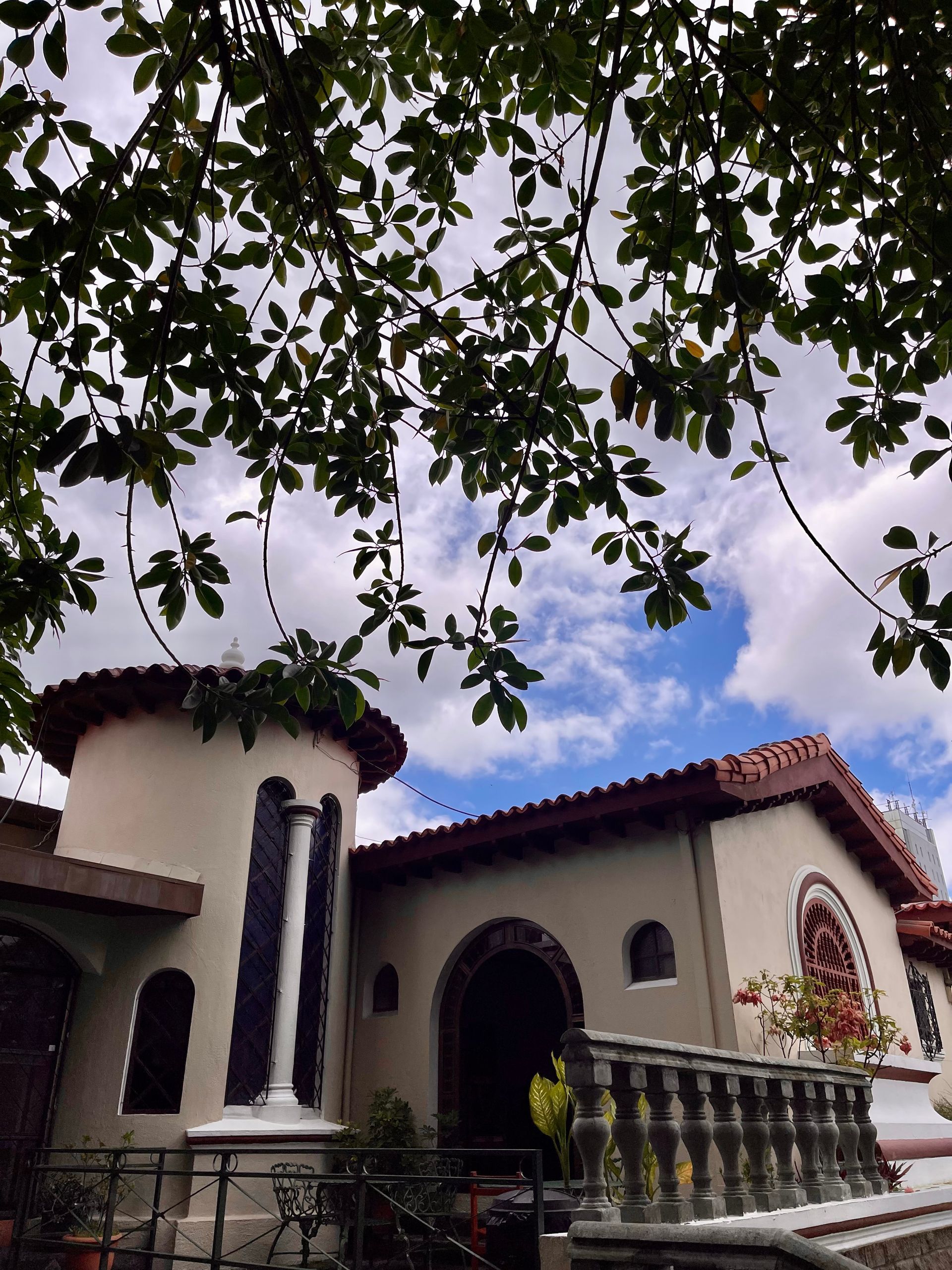 A house with a balcony and trees in front of it