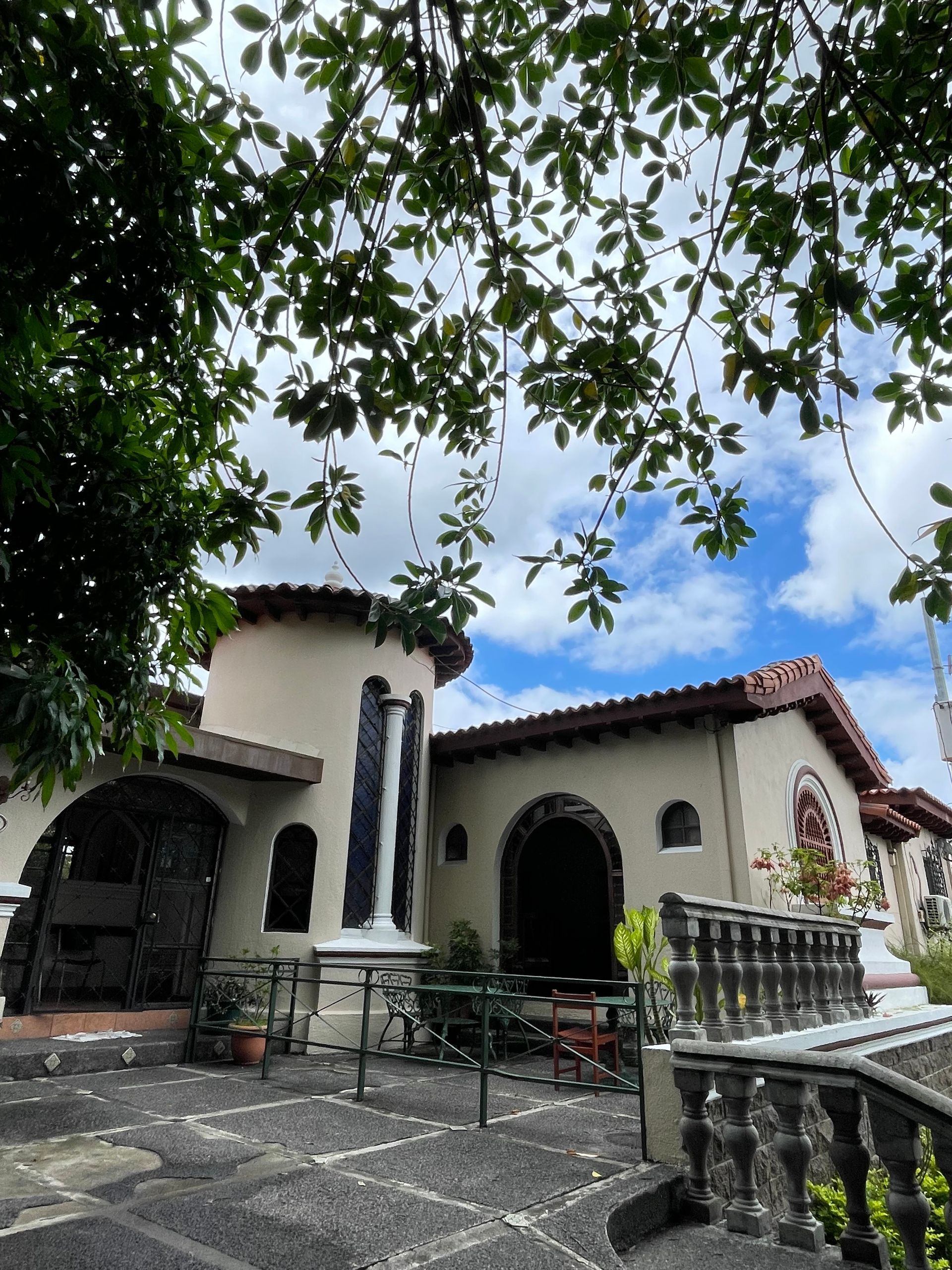 A white house with a balcony and trees in front of it