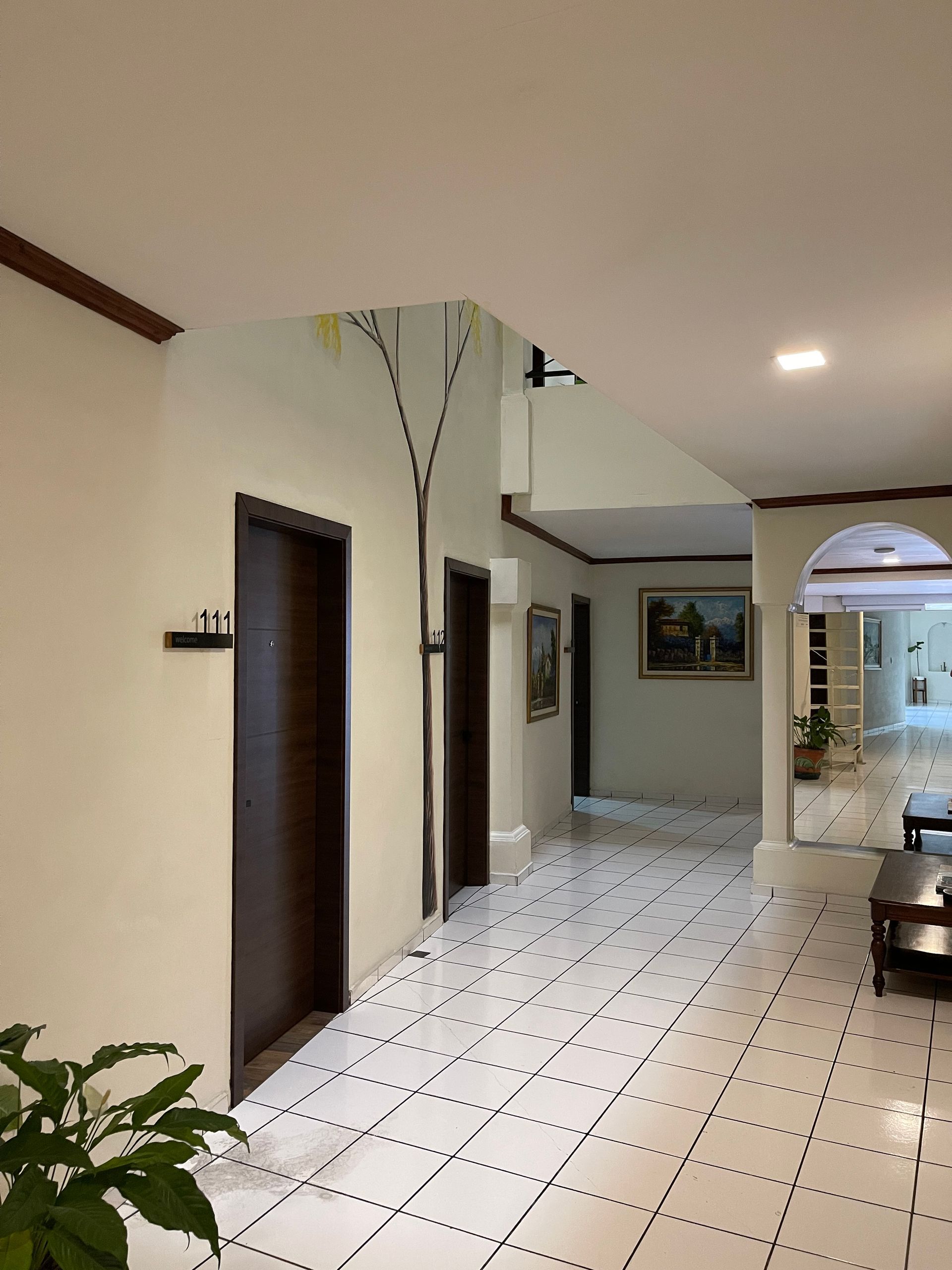 A hallway with white tile floors and brown doors