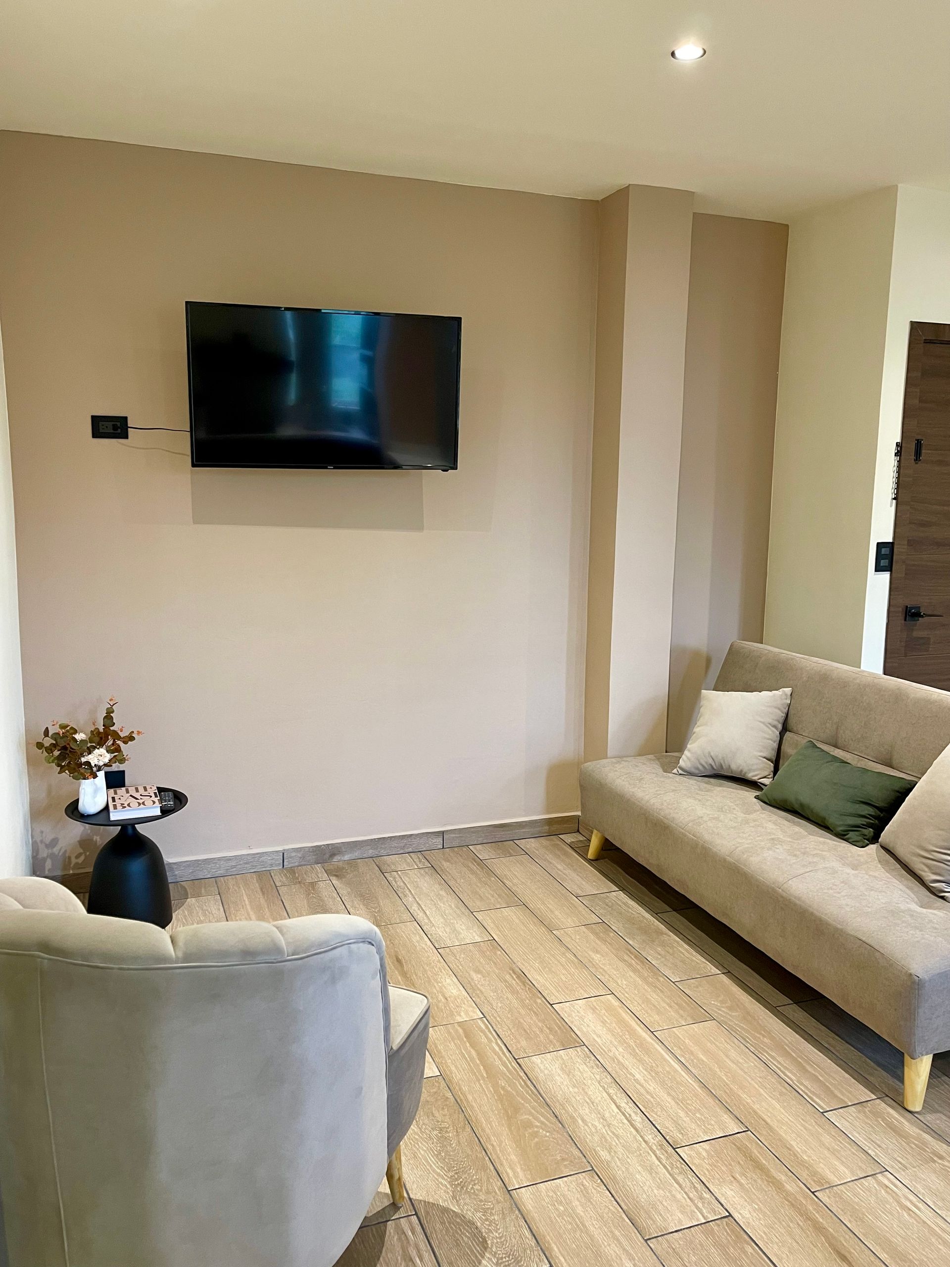 A living room with a couch , chair and television on the wall.