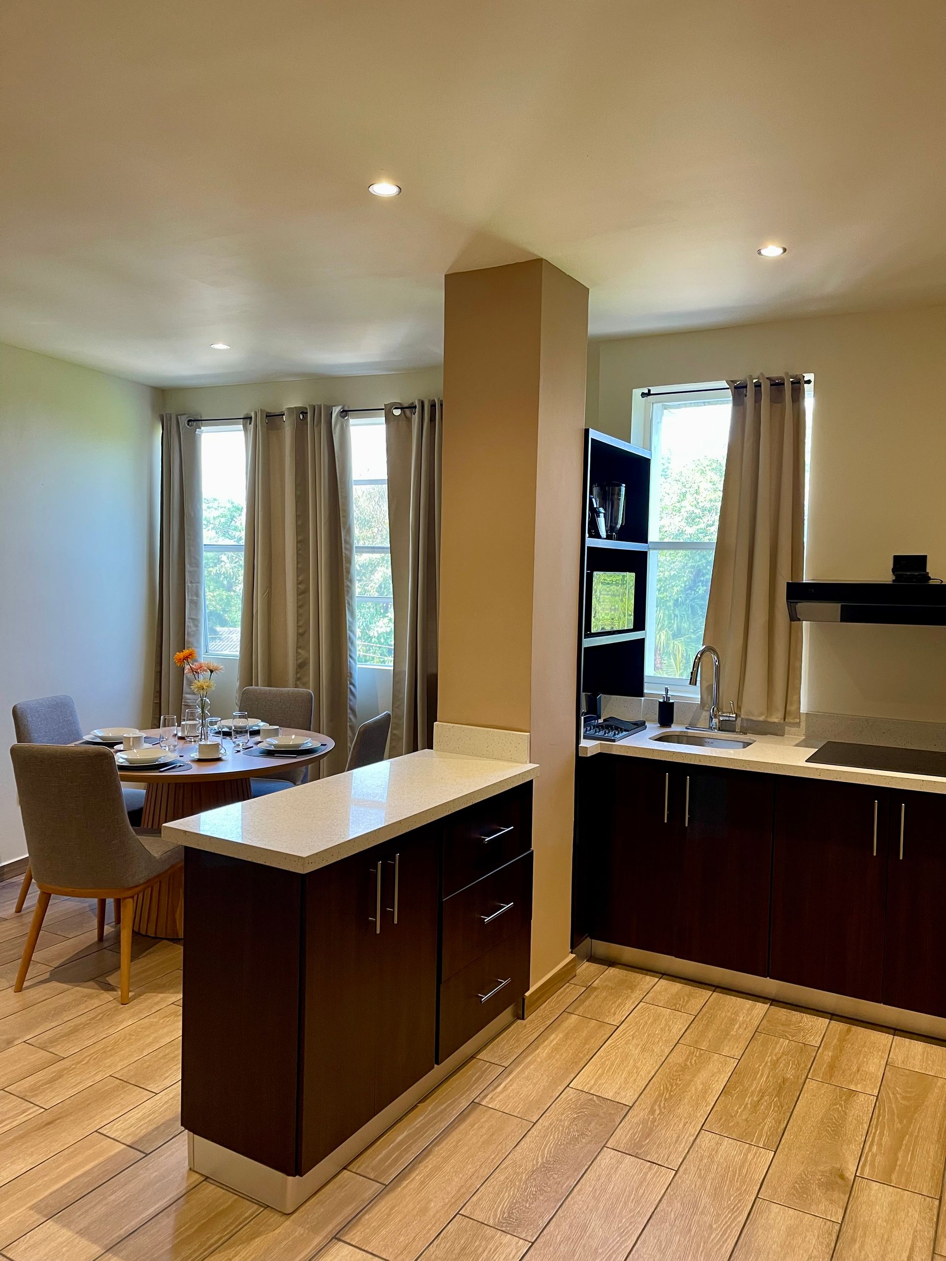 A kitchen with a table and chairs in it and a dining room in the background.