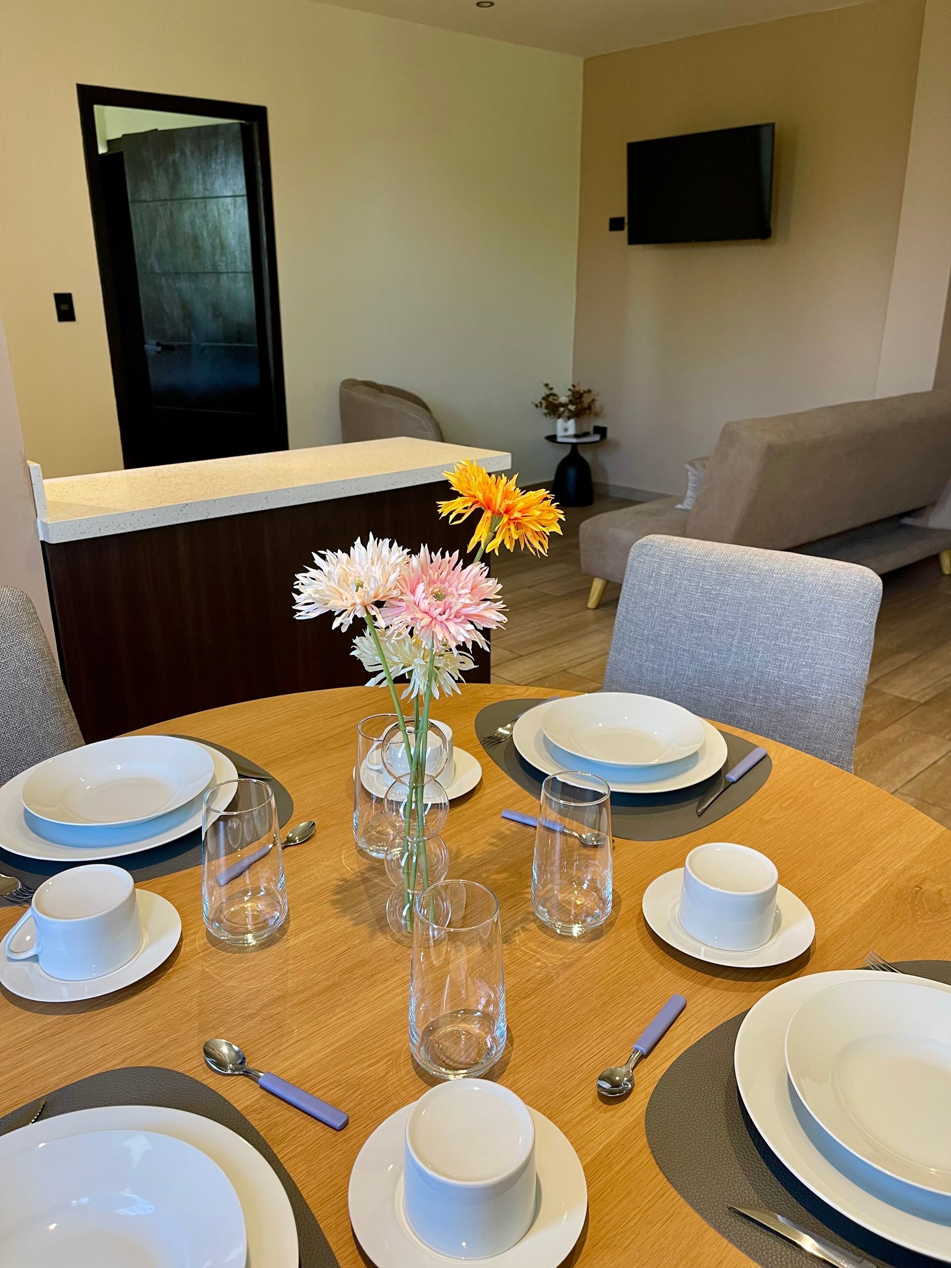 A table with plates , cups , glasses and a vase of flowers on it