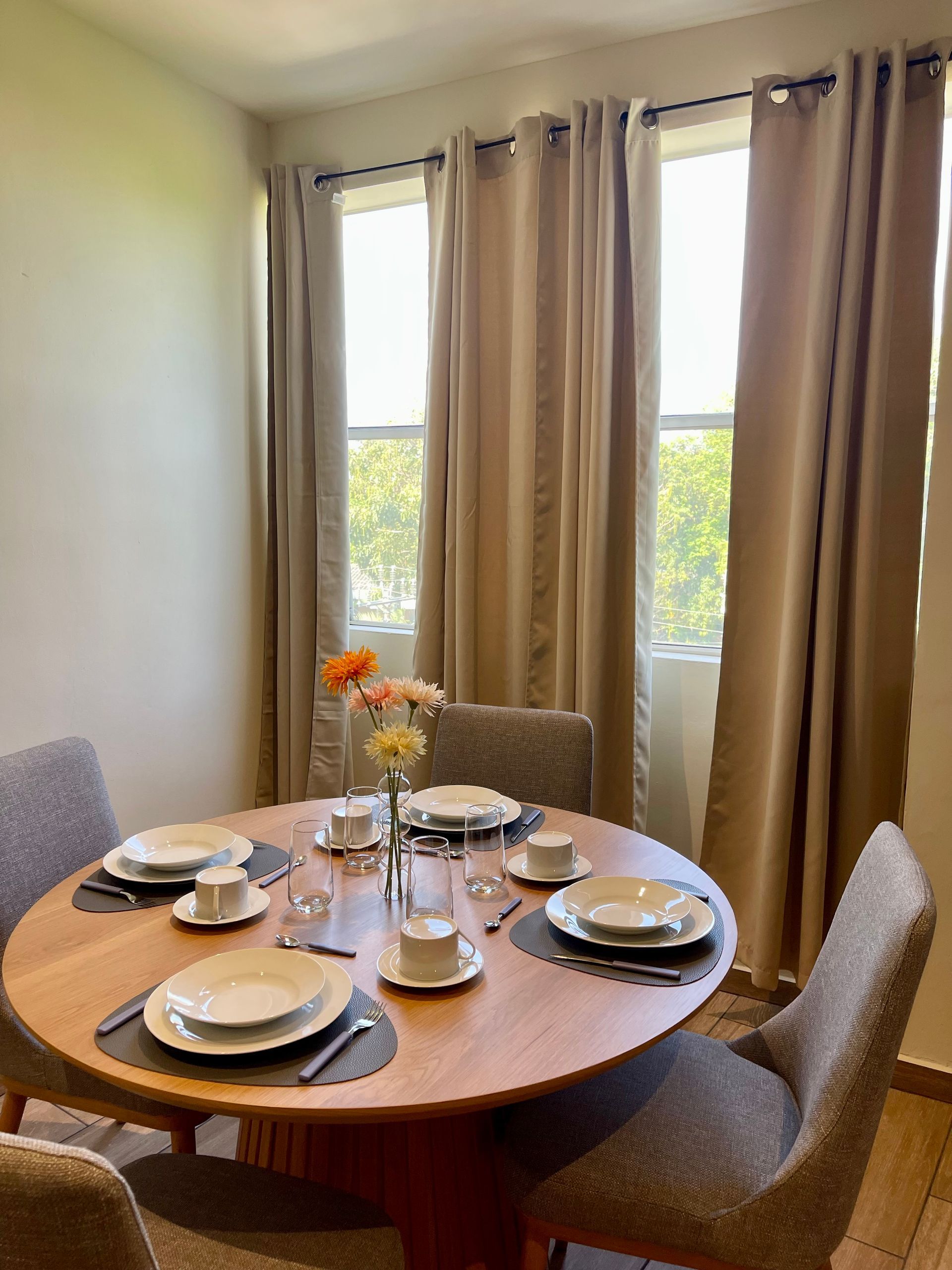 A dining room with a round table and chairs and plates on it.