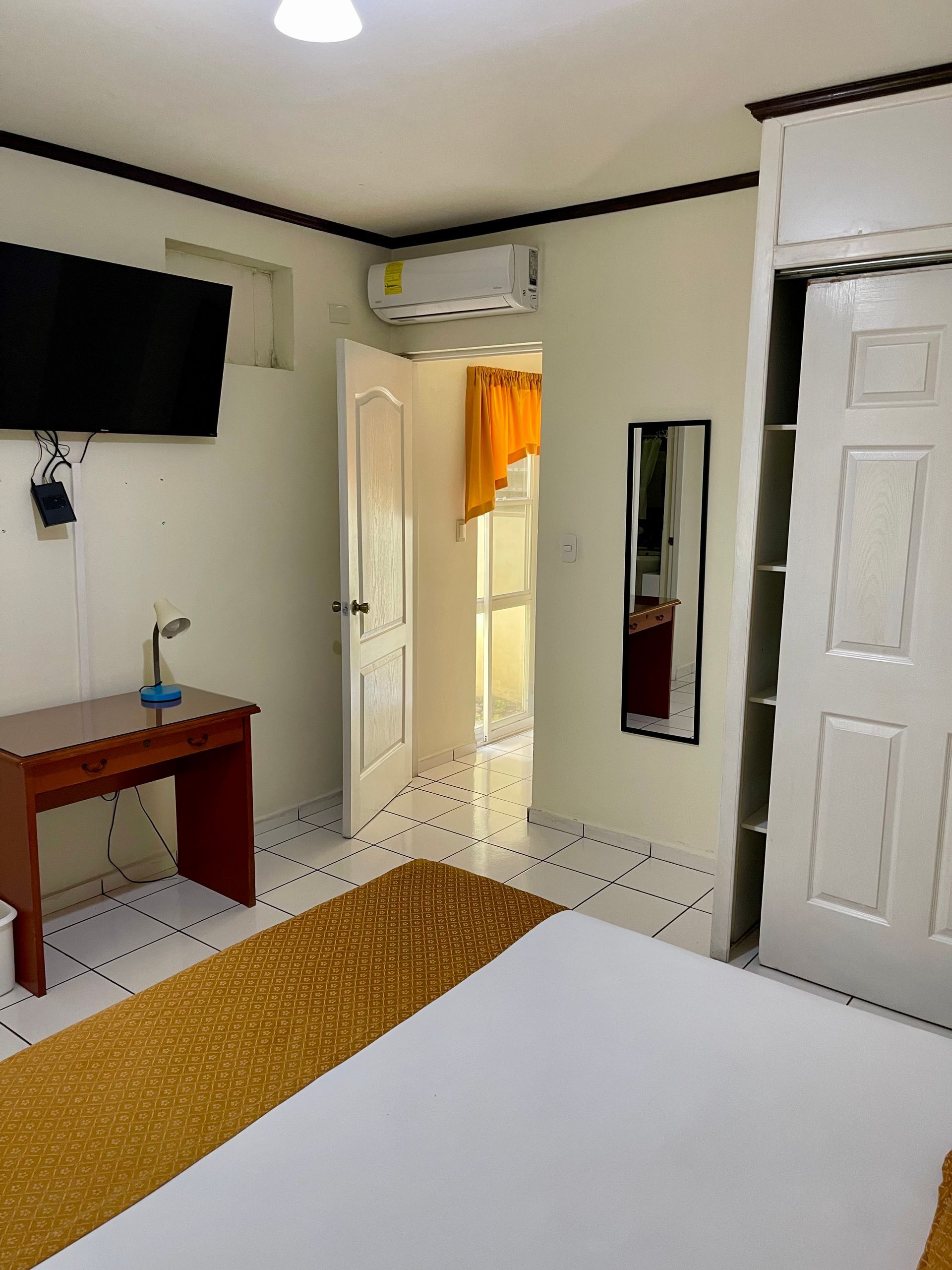 A bedroom with a bed , desk , television and mirror