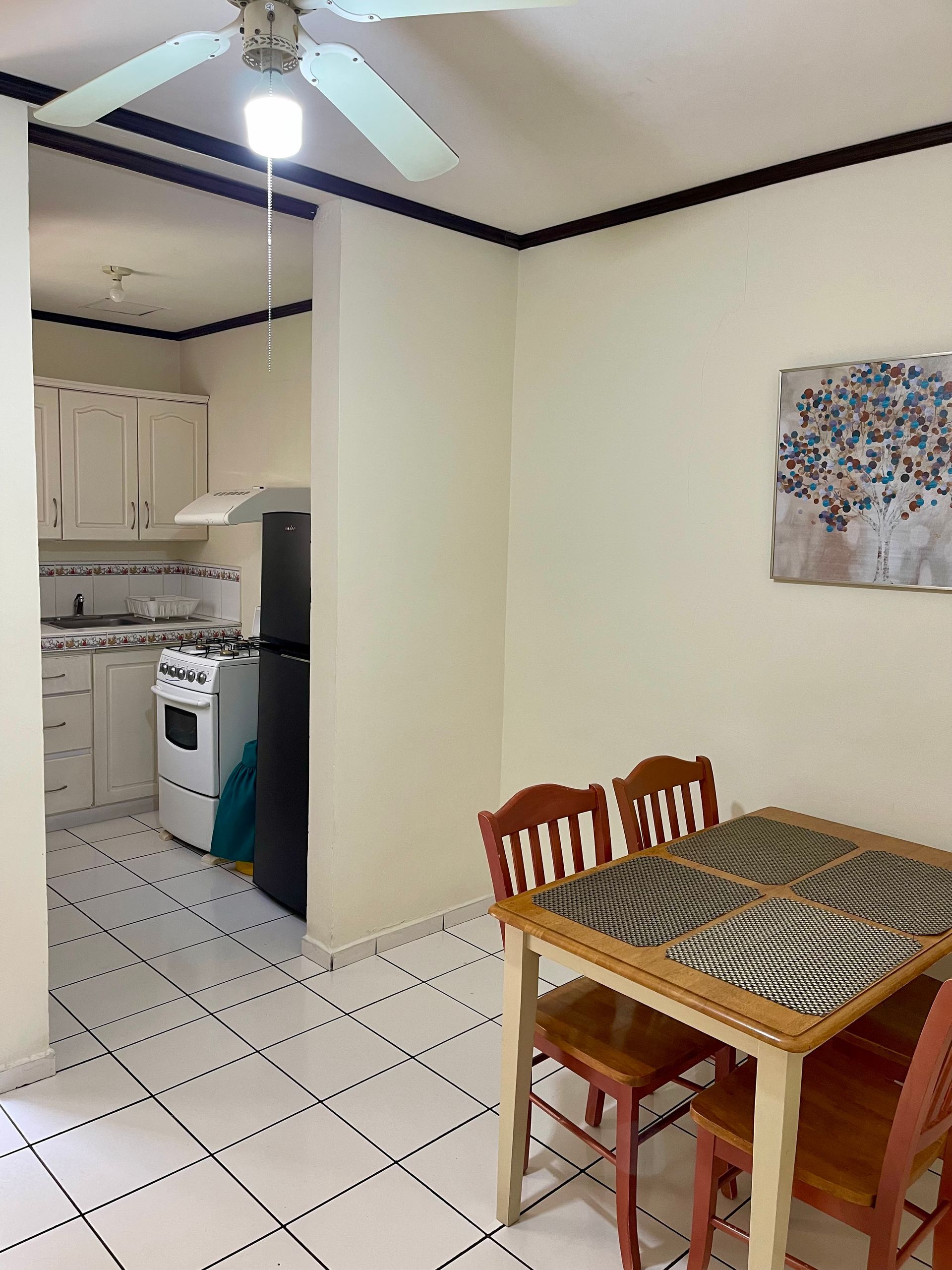 A kitchen with a table and chairs and a ceiling fan