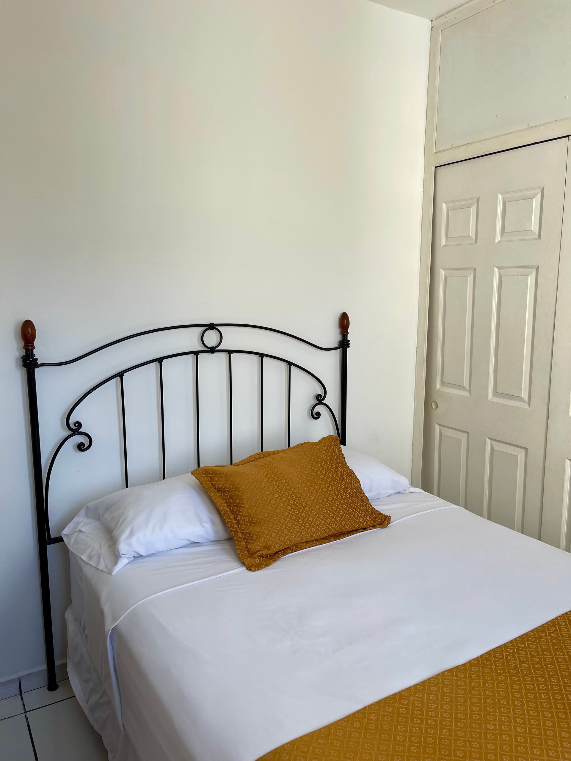 A bed with white sheets and a yellow pillow in a bedroom
